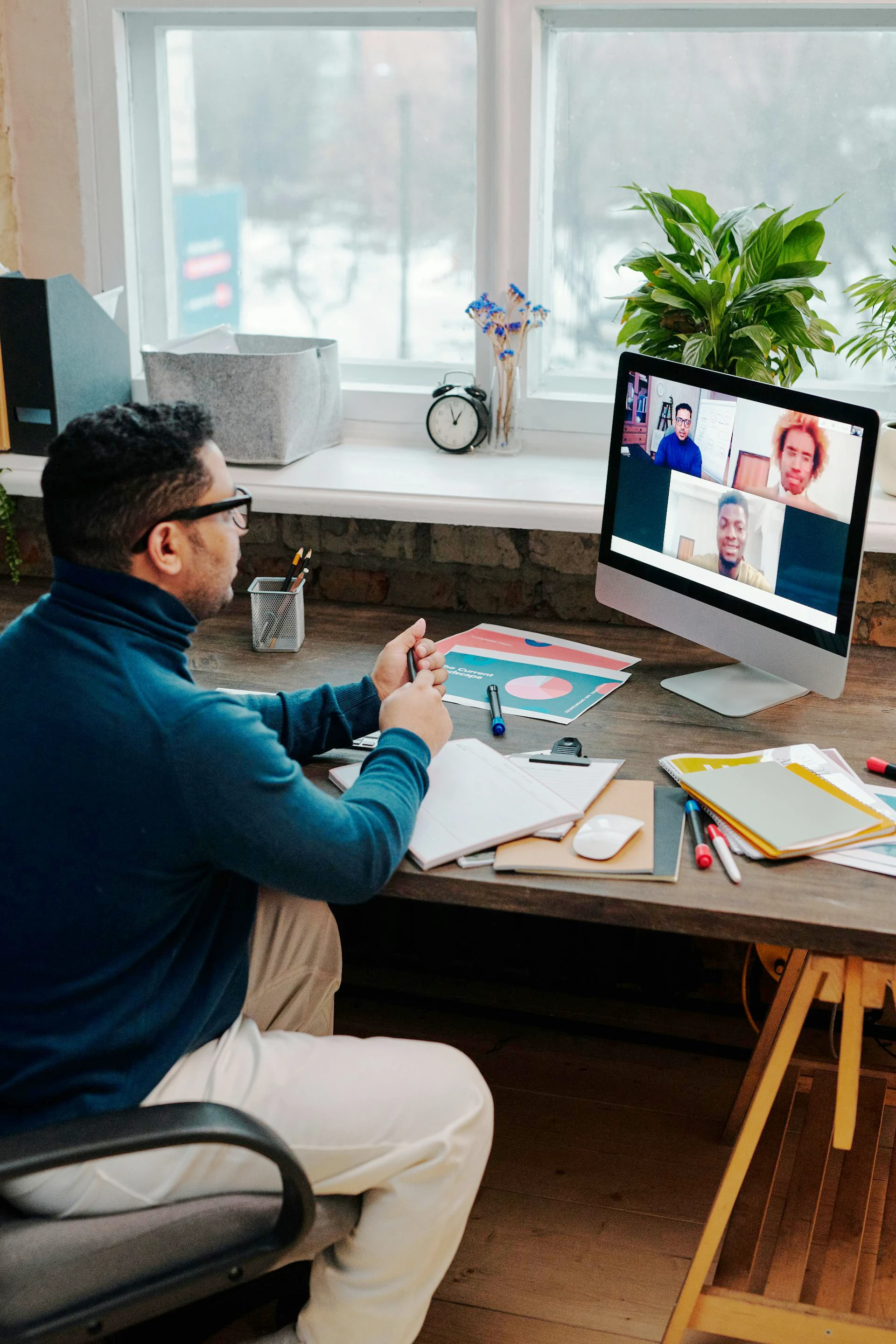 Homme assis dans son bureau faisant une visioconférence avec trois autres personnes