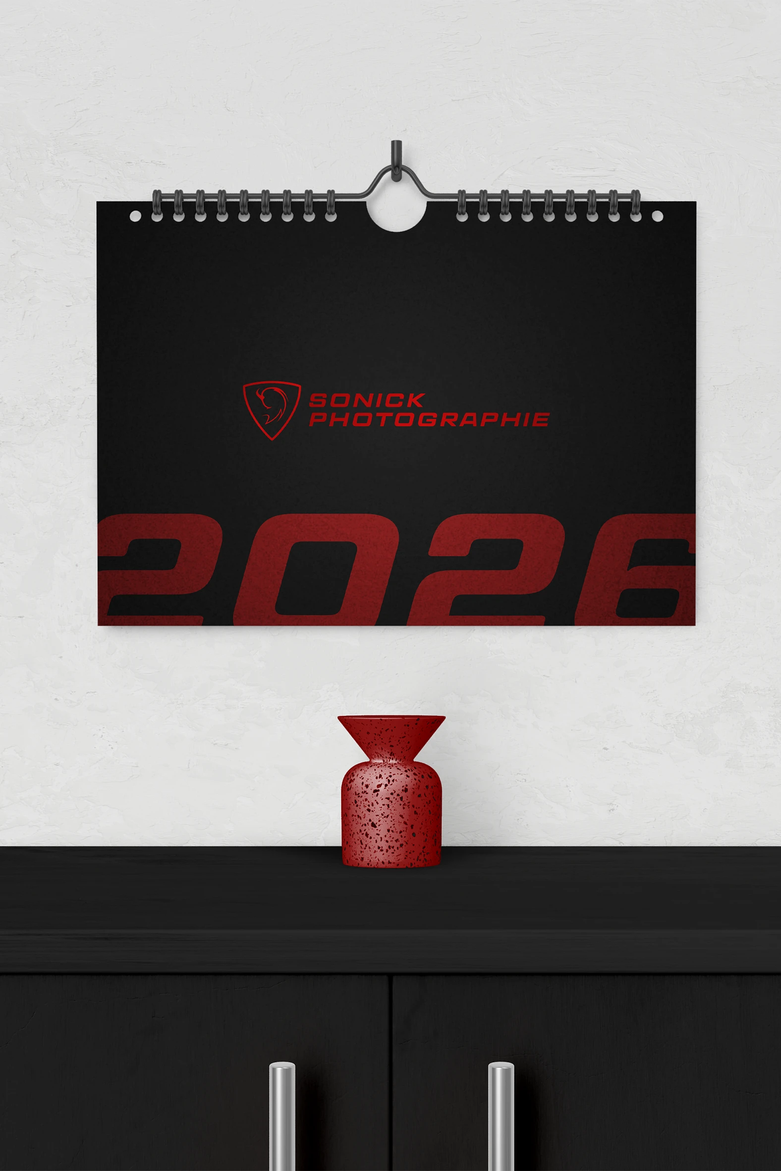 Calendrier noir Sonick Photographie 2026 accroché sur un mur blanc