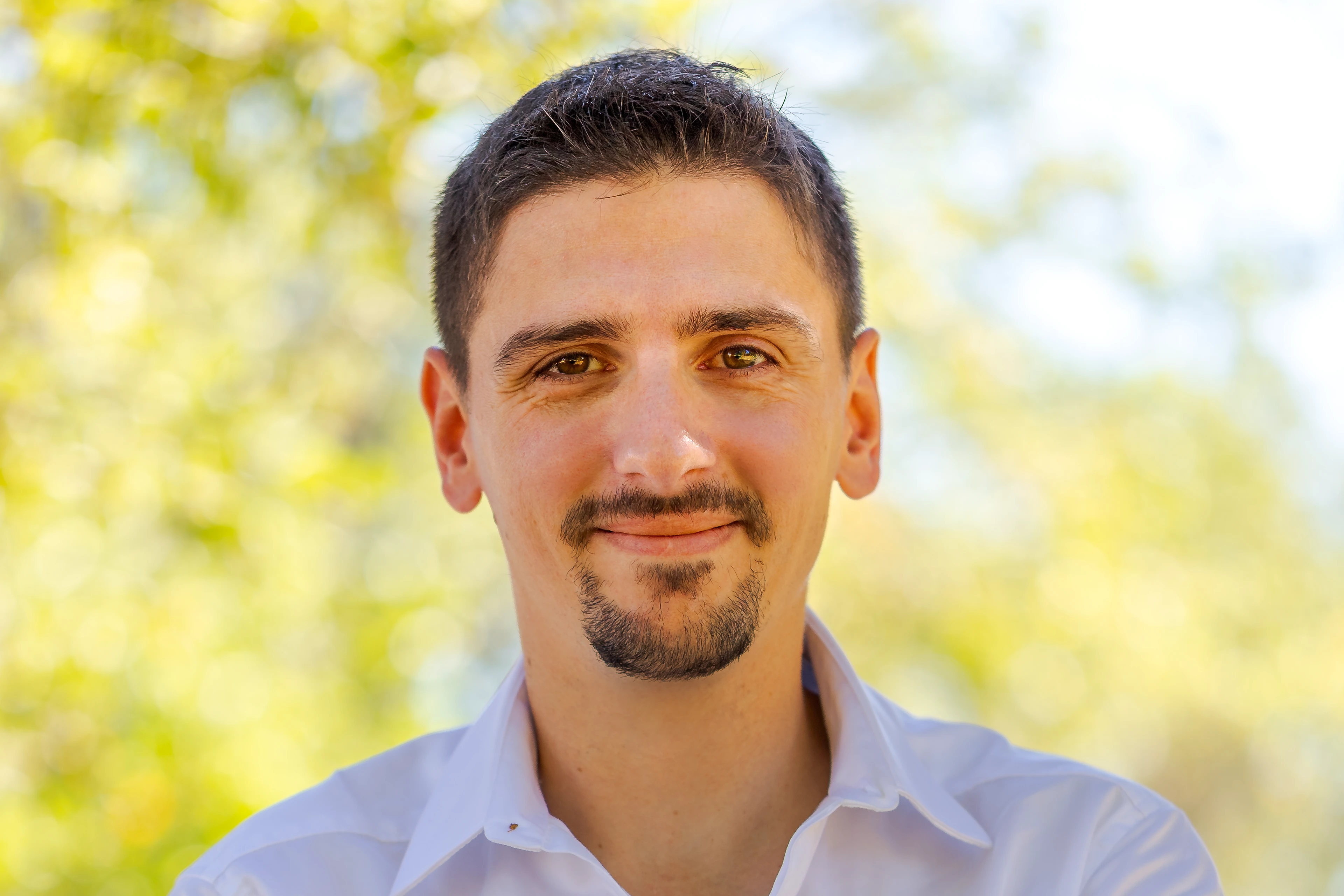 Yannick Soler avec une chemise blanche sur fond naturel