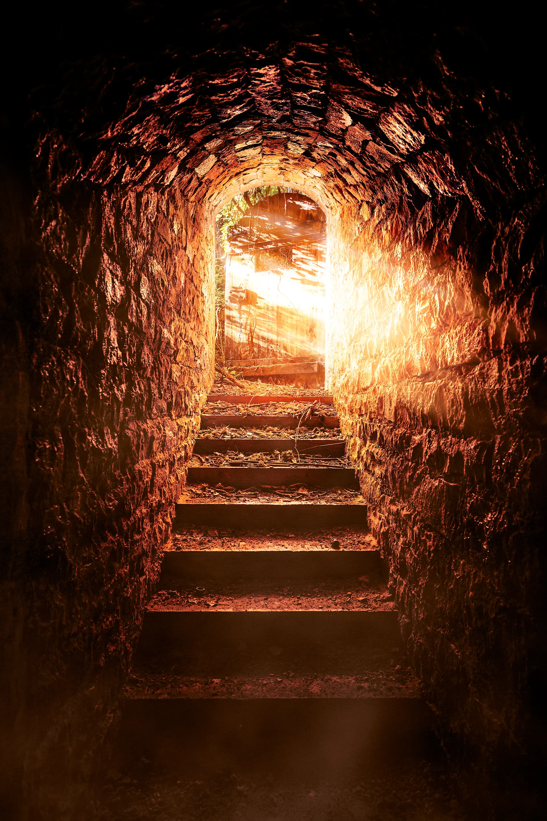 Escalier d'un site urbex, le fort de Varois en Côte d'Or, donnant sur une porte entrouverte qui laisse passer les rayons du soleil