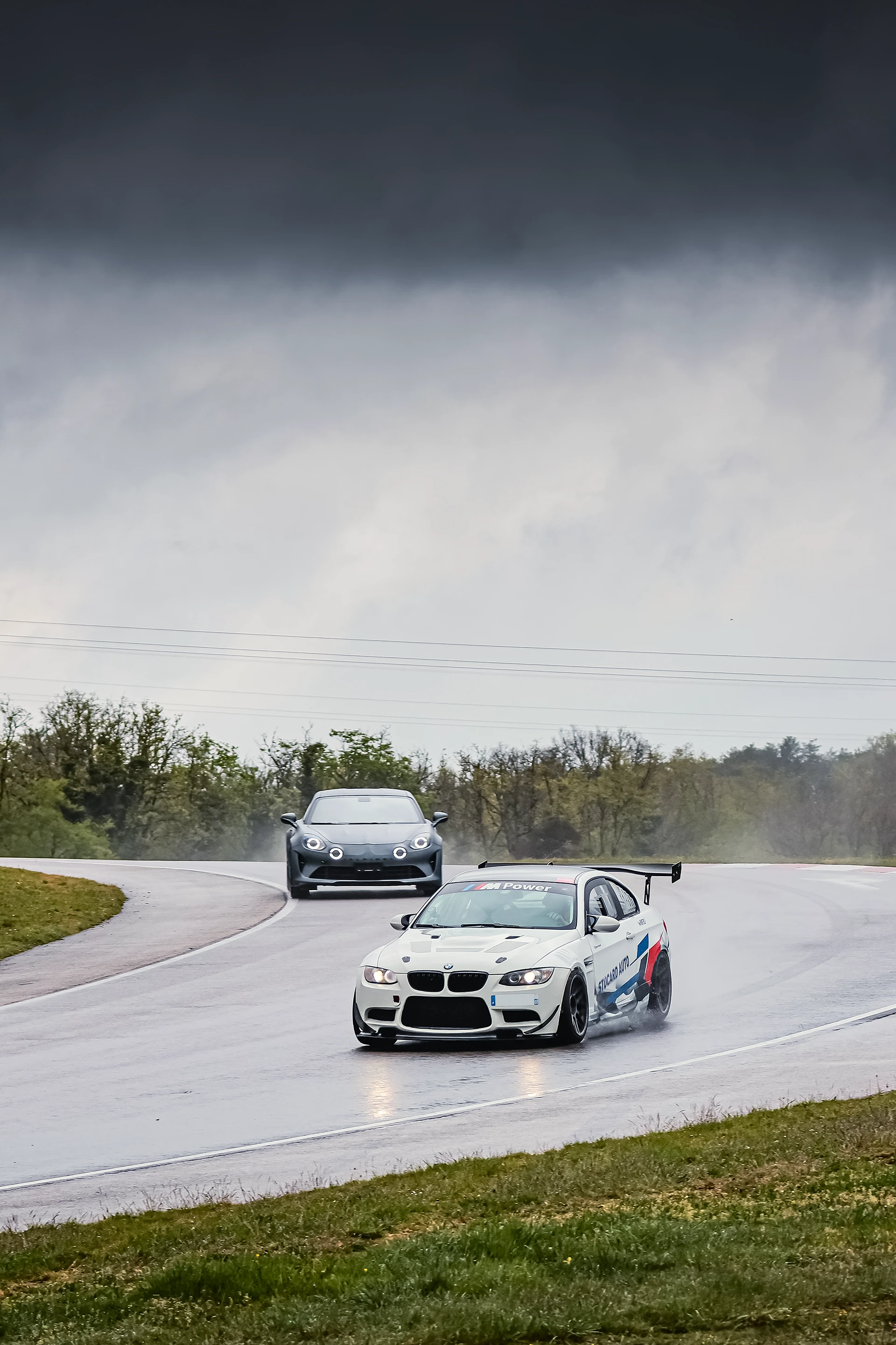BMW M3 E92 blanche et Alpine A110 grise sur le circuit de Dijon-Prenois sous la pluie