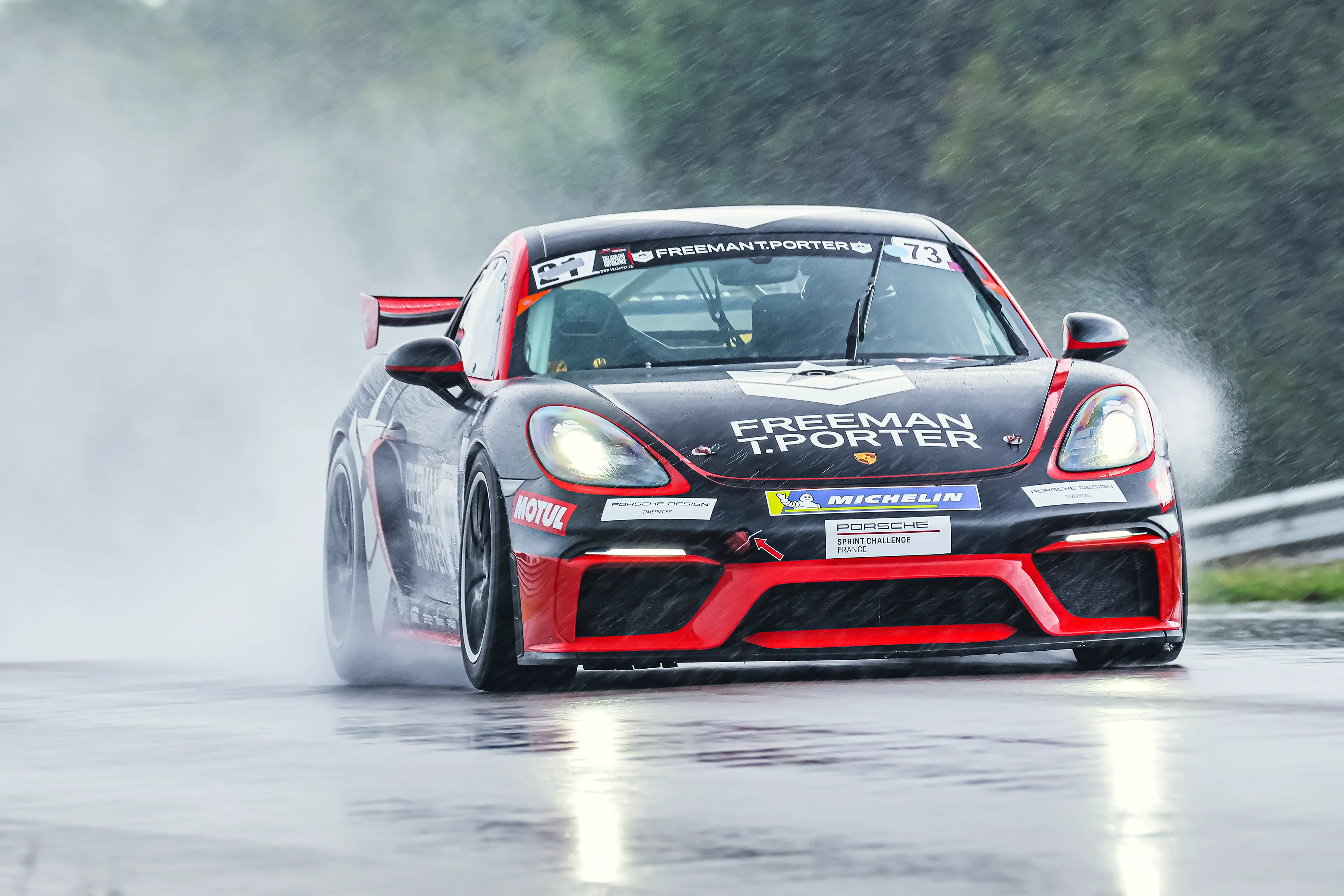 Porsche Cayman GT4RS Clubsport noire et rouge sous la pluie su le circuit de Dijon-Prenois