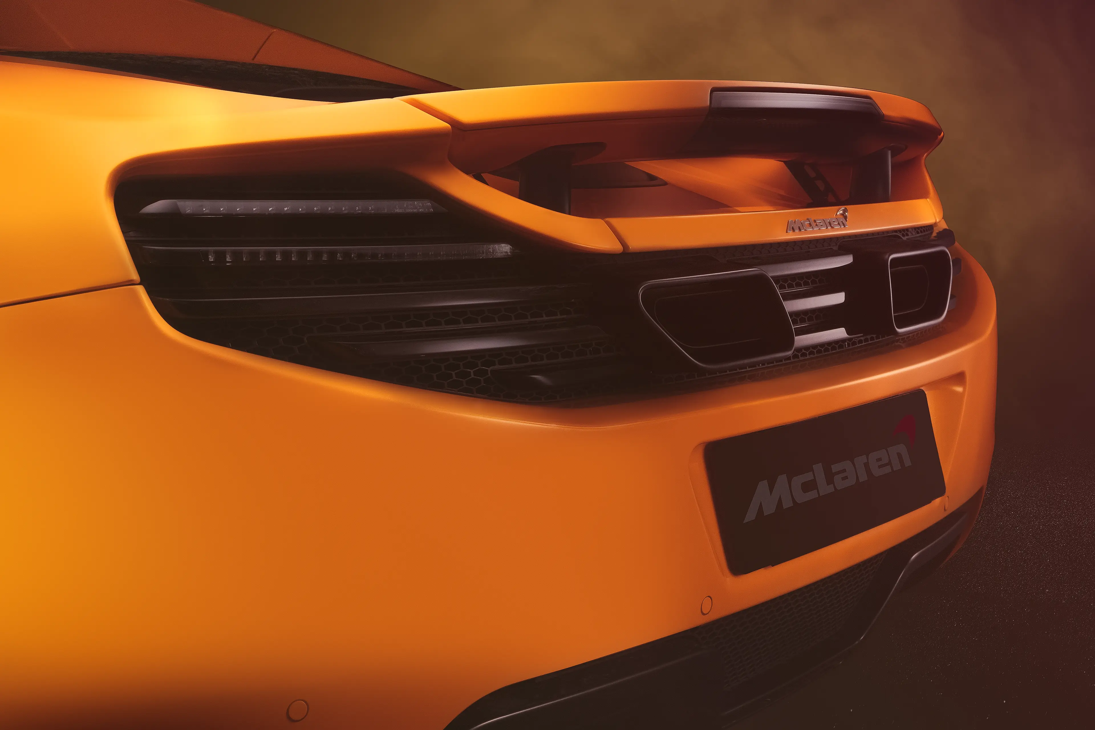 Arrière d'une McLaren MP4-12C orange papaye avec la technique FDL