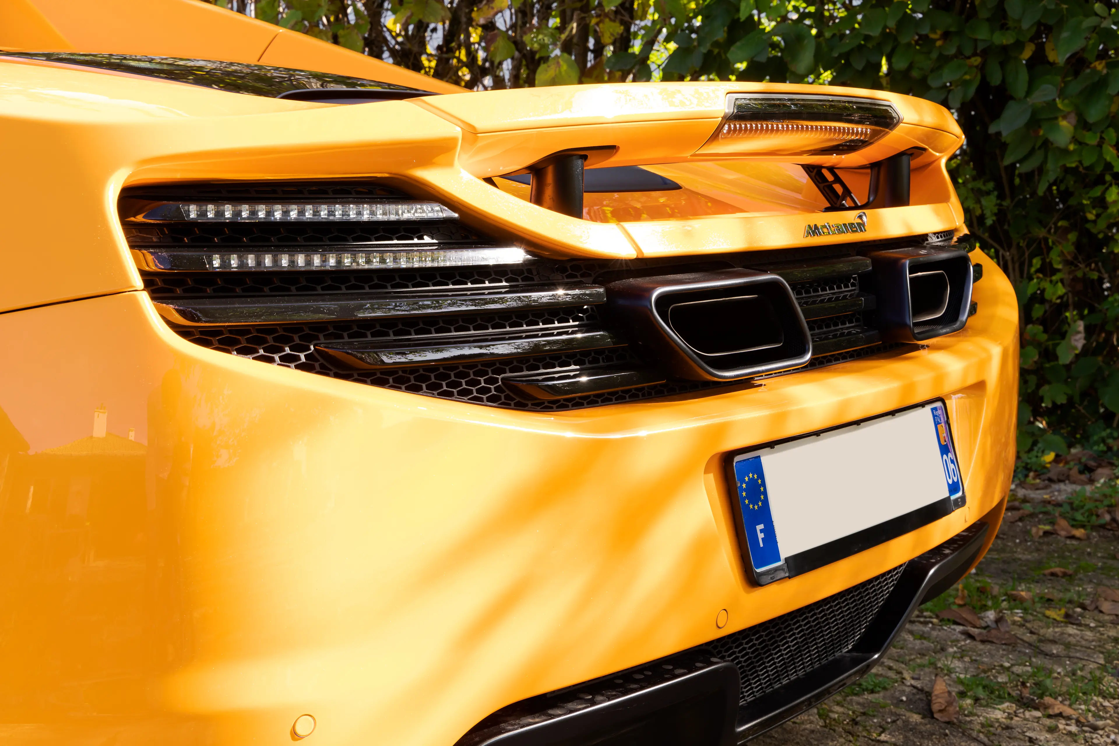 Arrière d'une McLaren MP4-12C orange papaye dans une cour