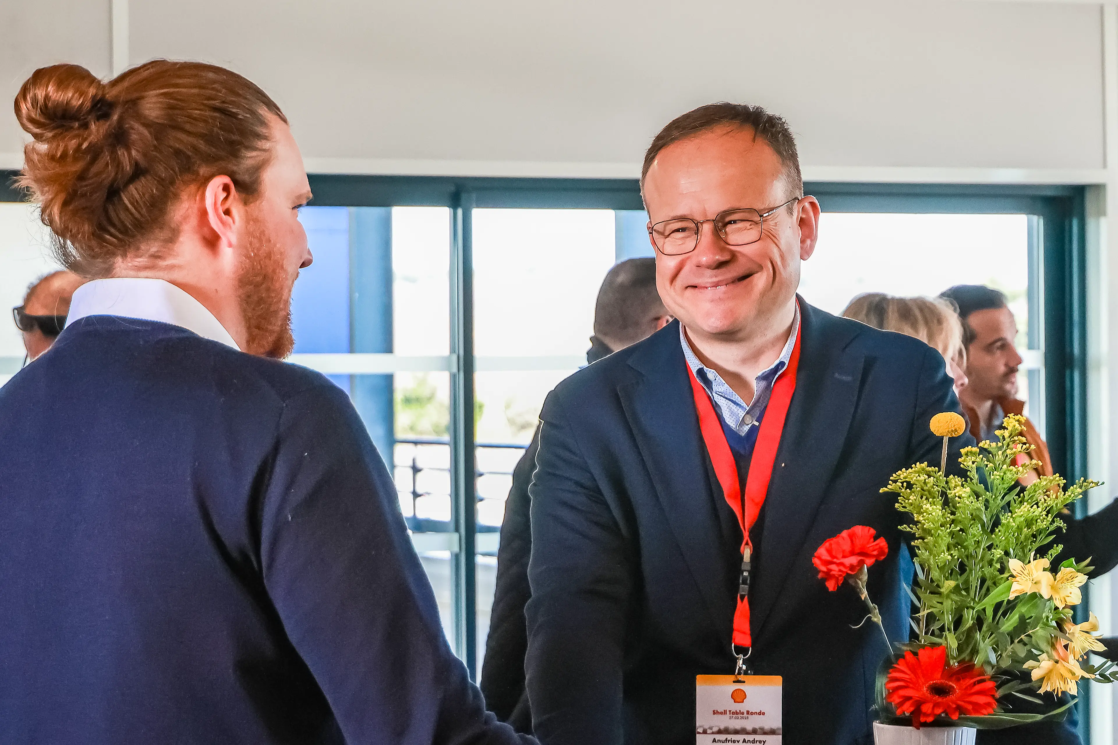Homme salarié Shell souriant à un autre salarié lors d'un séminaire