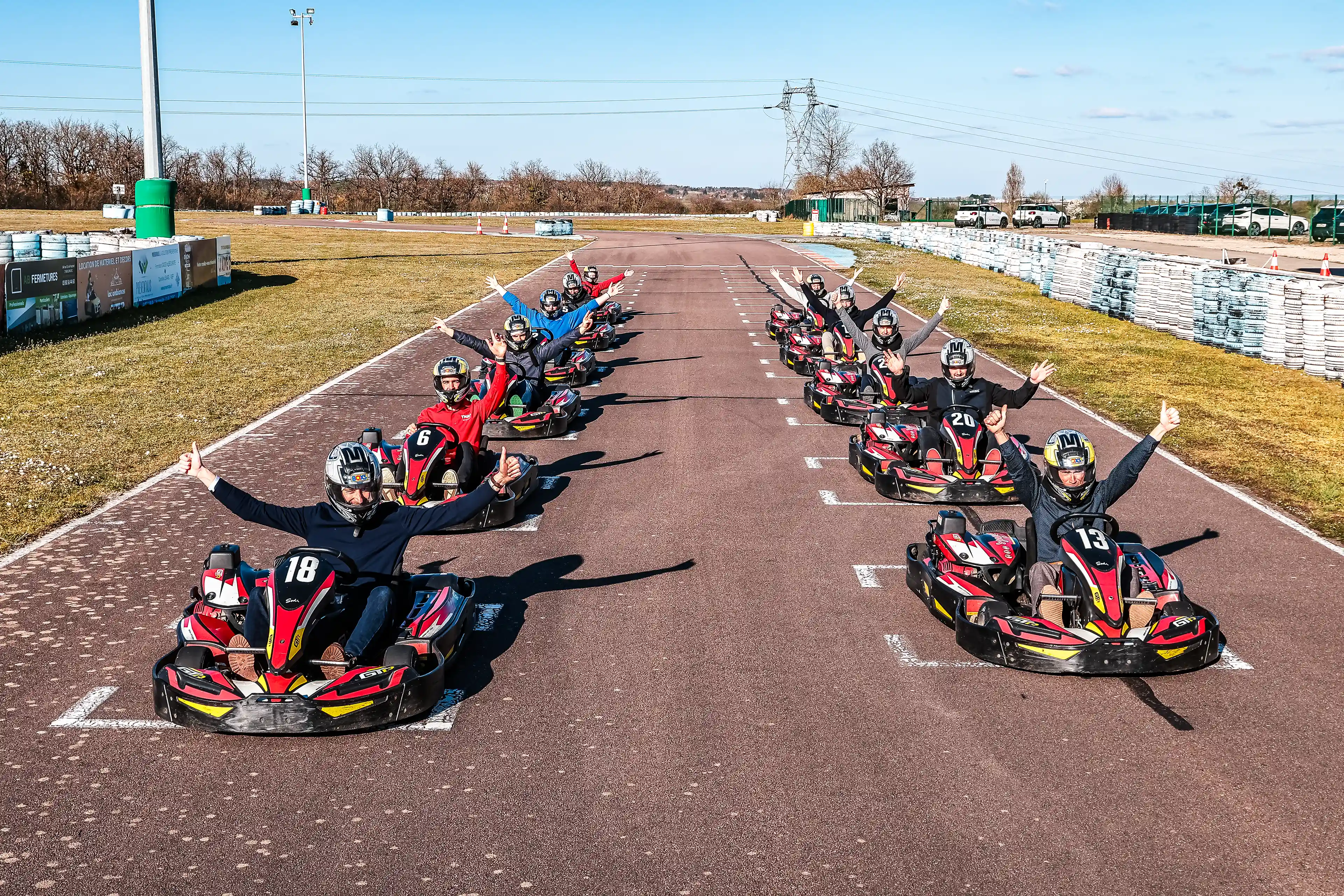Pilotes de karting sur la ligne de départ levant les bras avec les pouces levés
