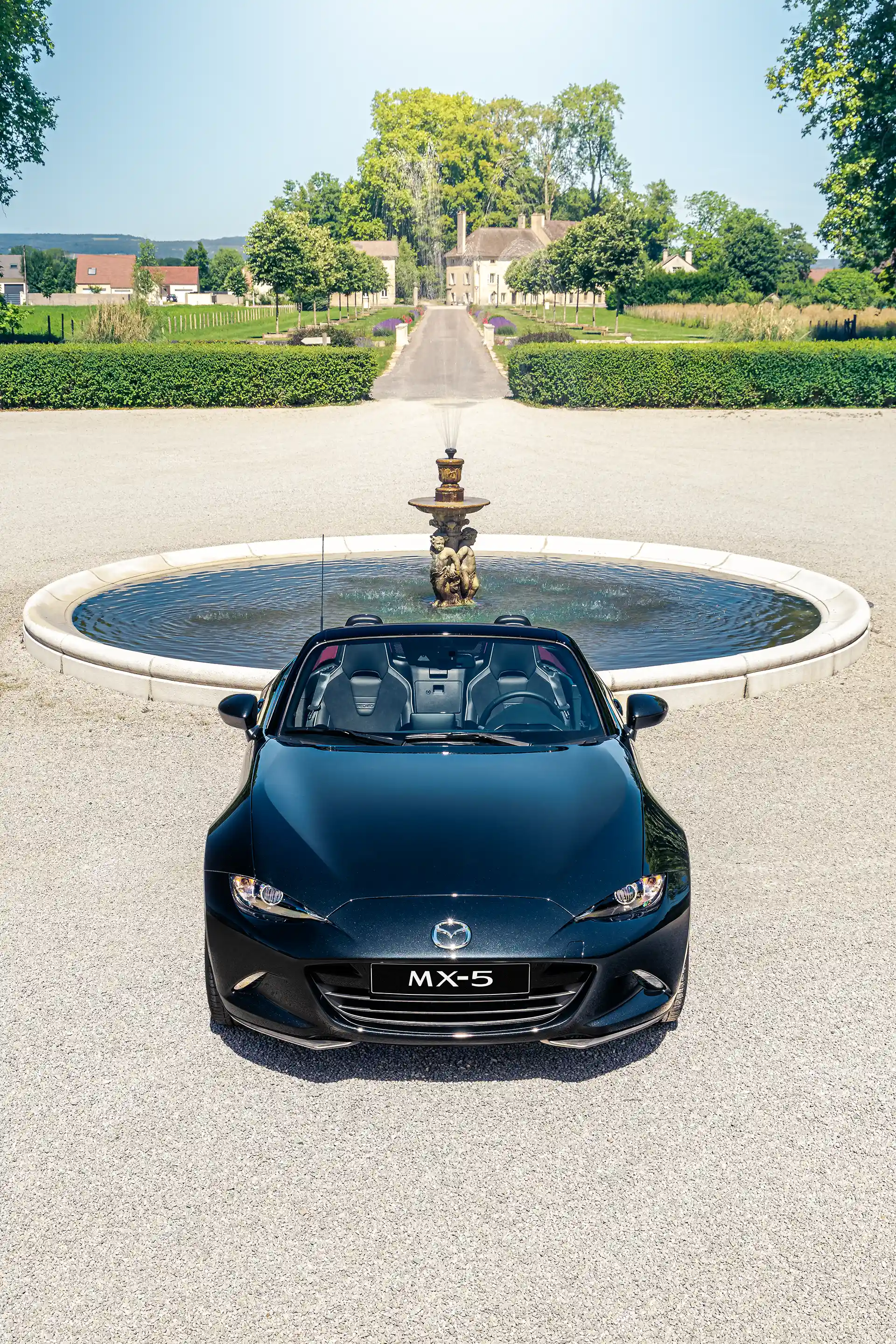 Face avant d'une Mazda MX-5 ND noire devant une fontaine