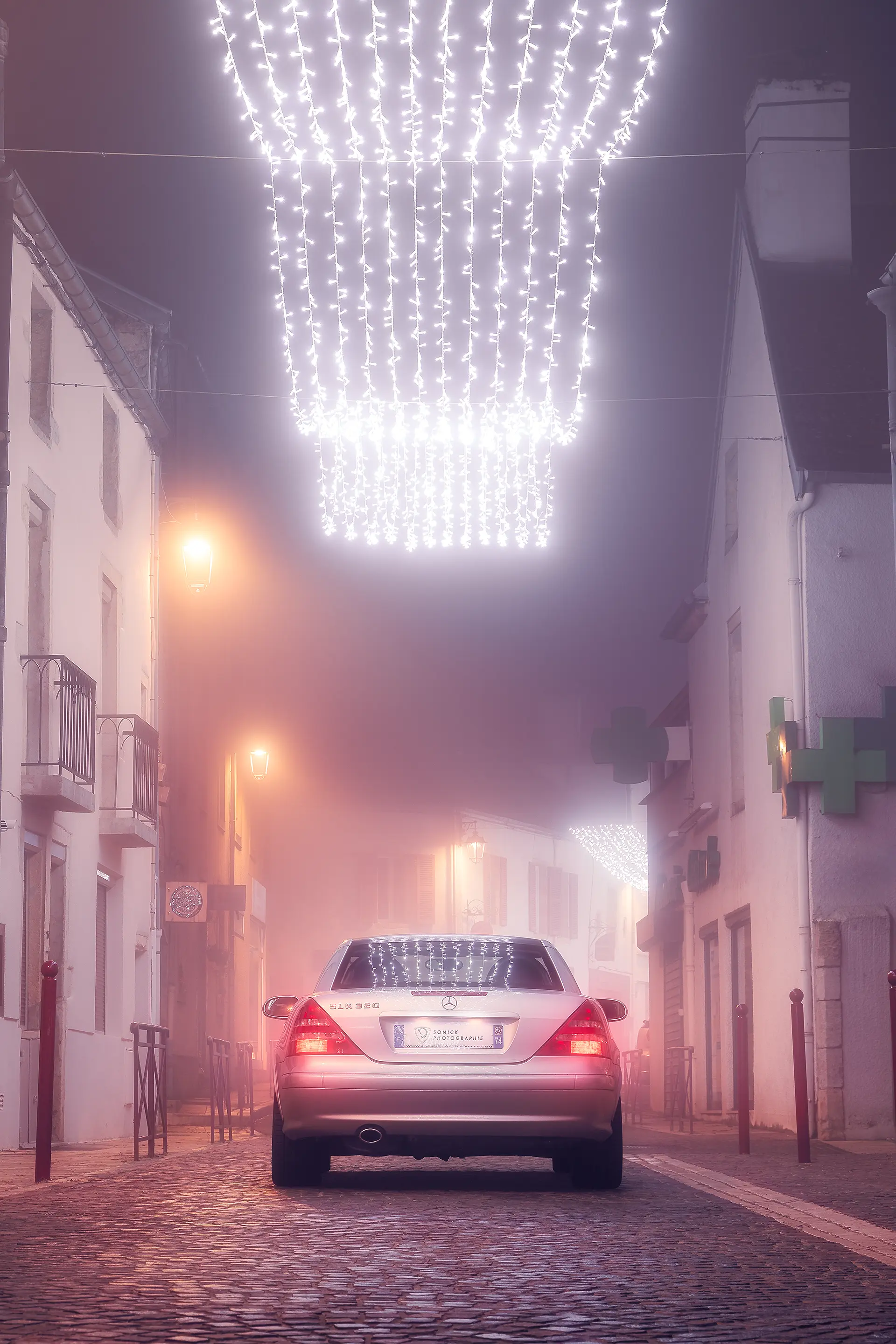 Arrière d'une Mercedes SLK R170 grise dans le brouillard dans une ruelle pavée à Noël