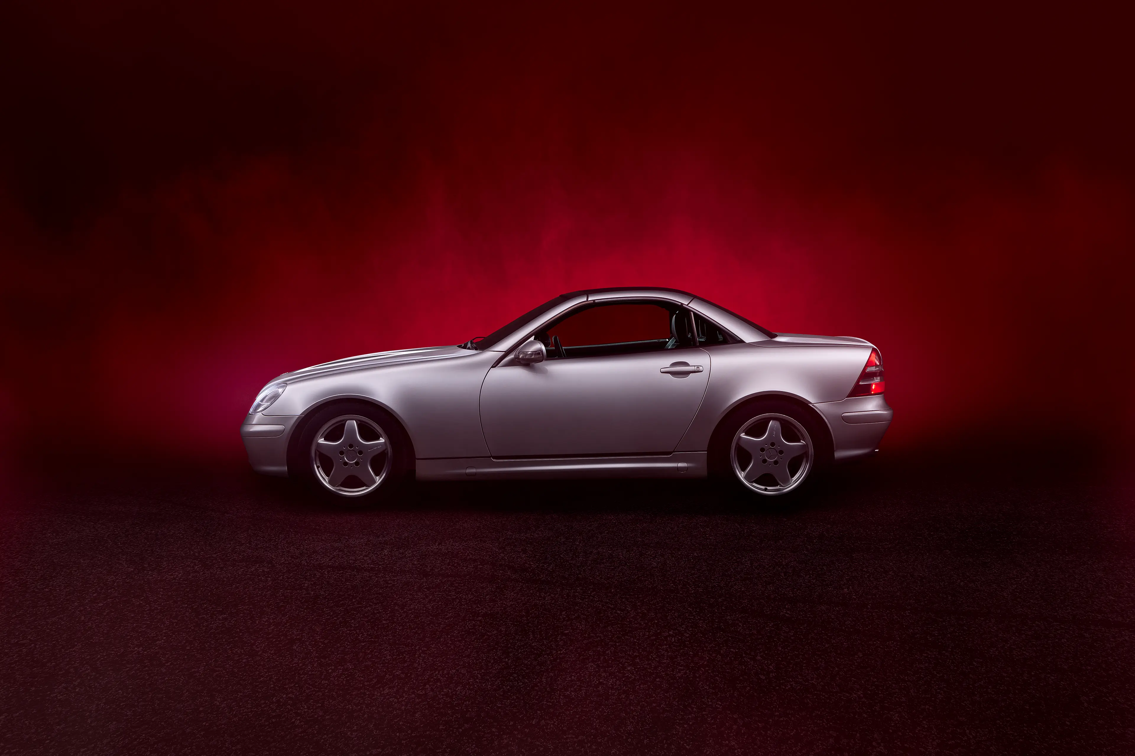 Mercedes SLK R170 grise de profil dans un brouillard de fumée rouge