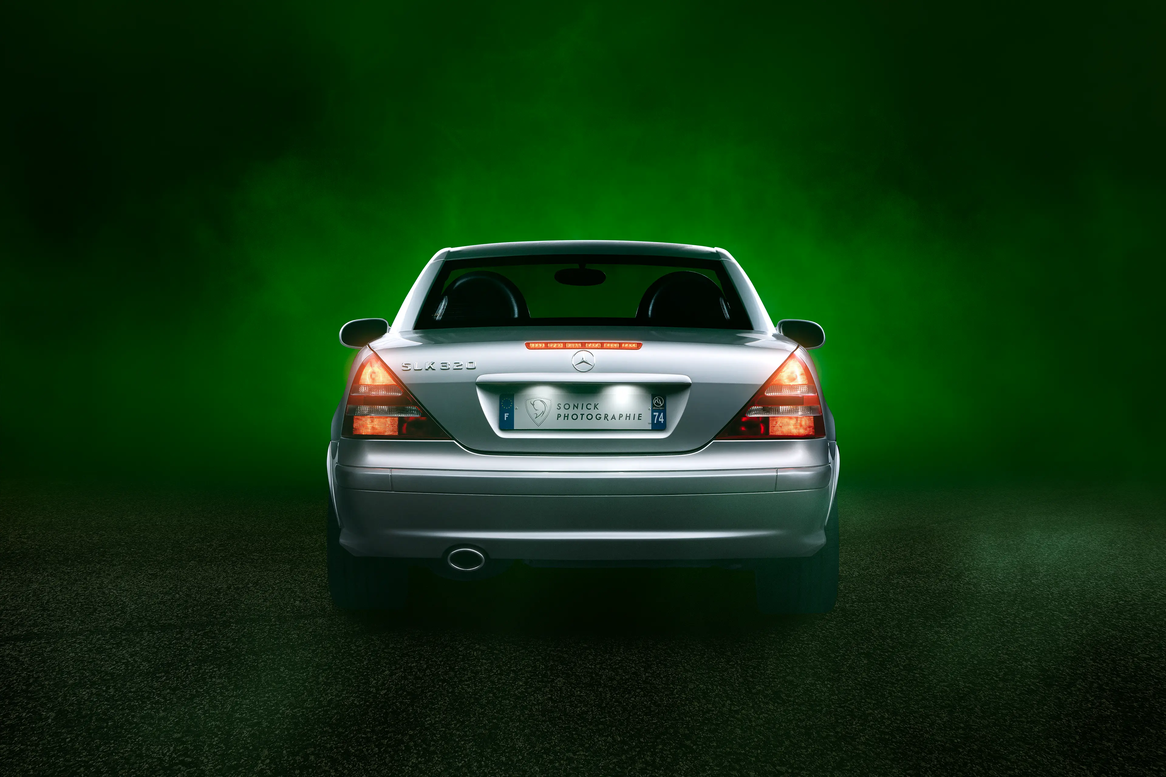 Arrière d'une Mercedes SLK R170 grise dans un brouillard de fumée vert