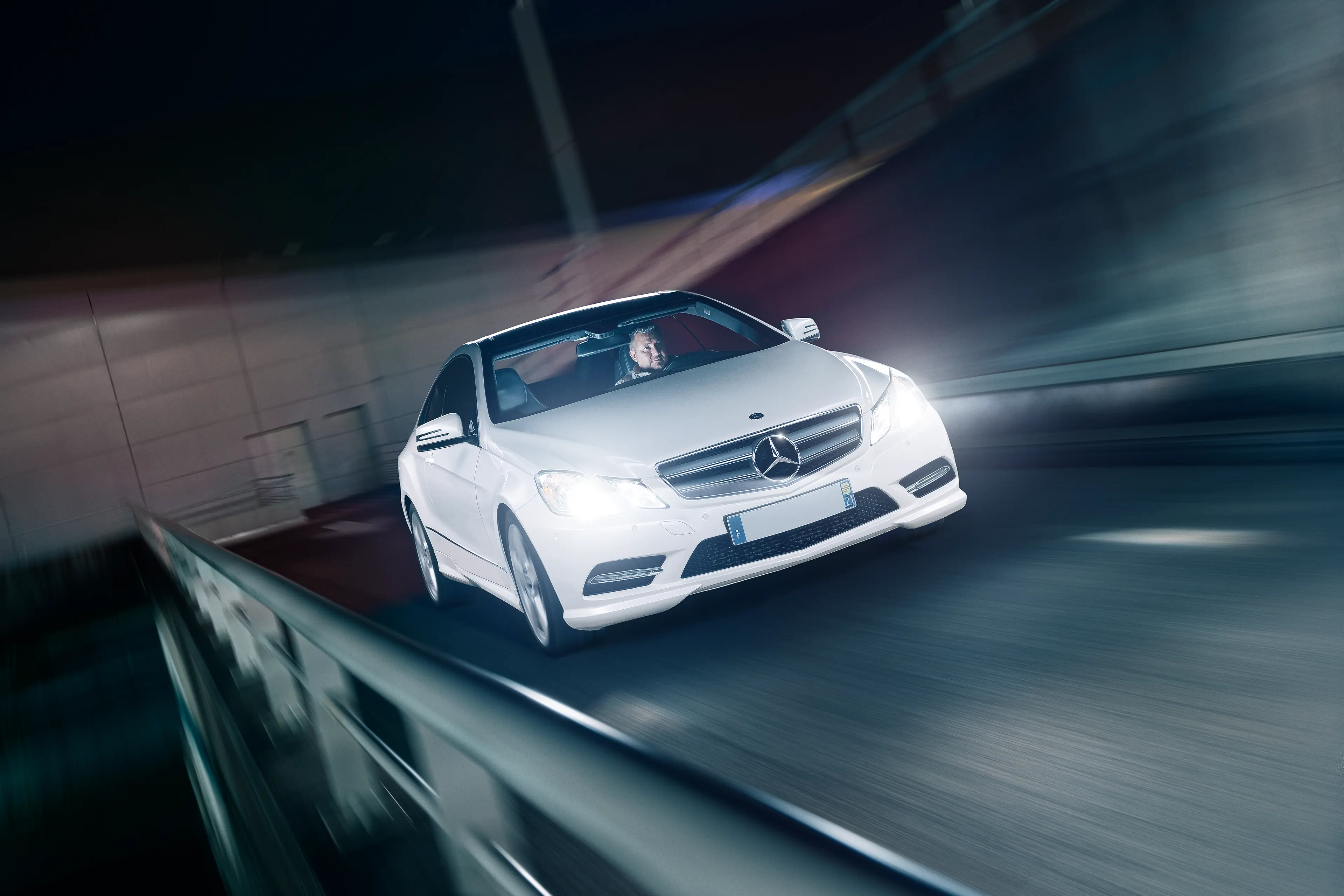 Mercedes Classe E coupé W212 blanche de 3/4 avant roulant dans un parking de nuit