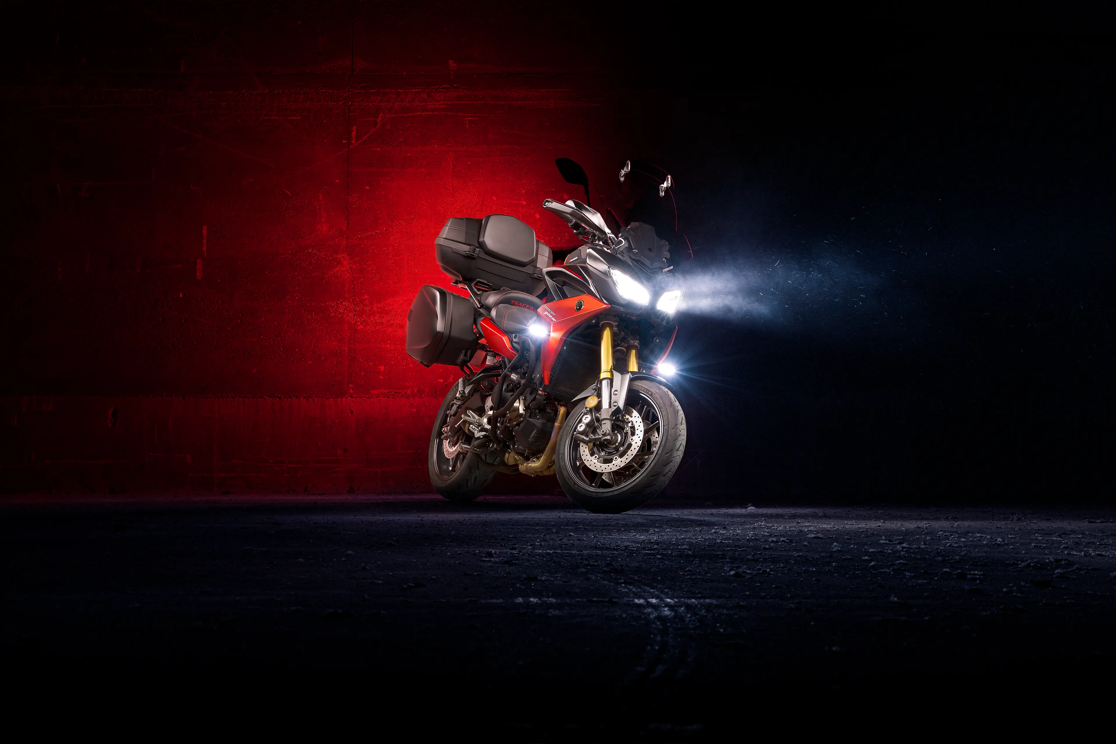 Yamaha Tracer 900GT rouge de 3/4 avant dans un entrepôt sombre et poussérieux en light painting