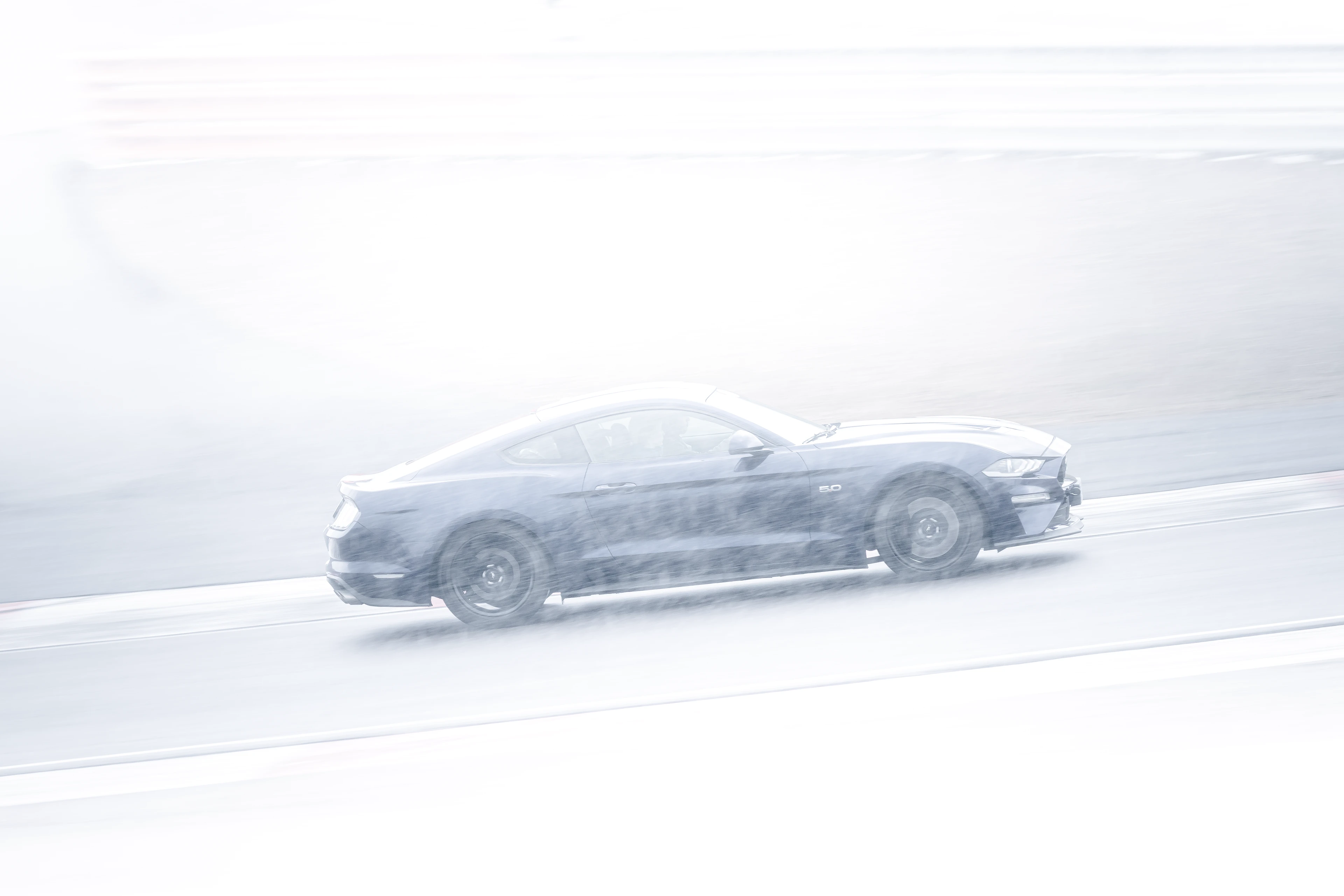 Ford Mustang noire sur le circuit de Dijon-Prenois sous la neige