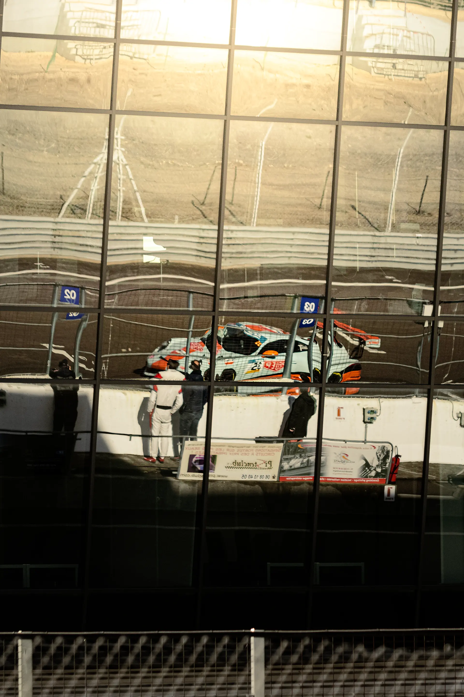 Porsche 911 Gulf dans le reflet des vitres de la direction de course sur le circuit de Dijon-Prenois