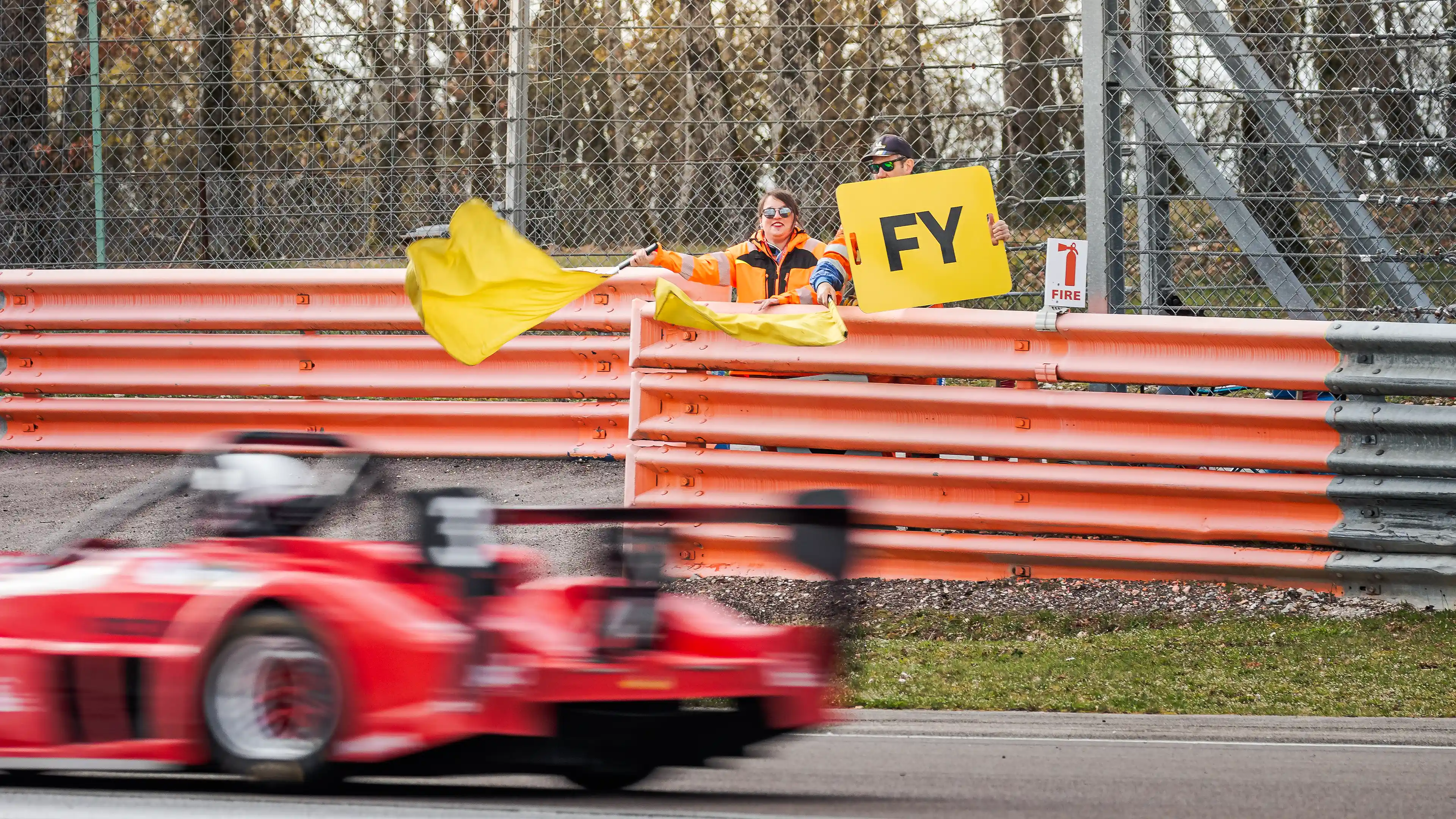 Comissaires de piste agitant un double drapeau jaune sur le circuit de Dijon-Prenois