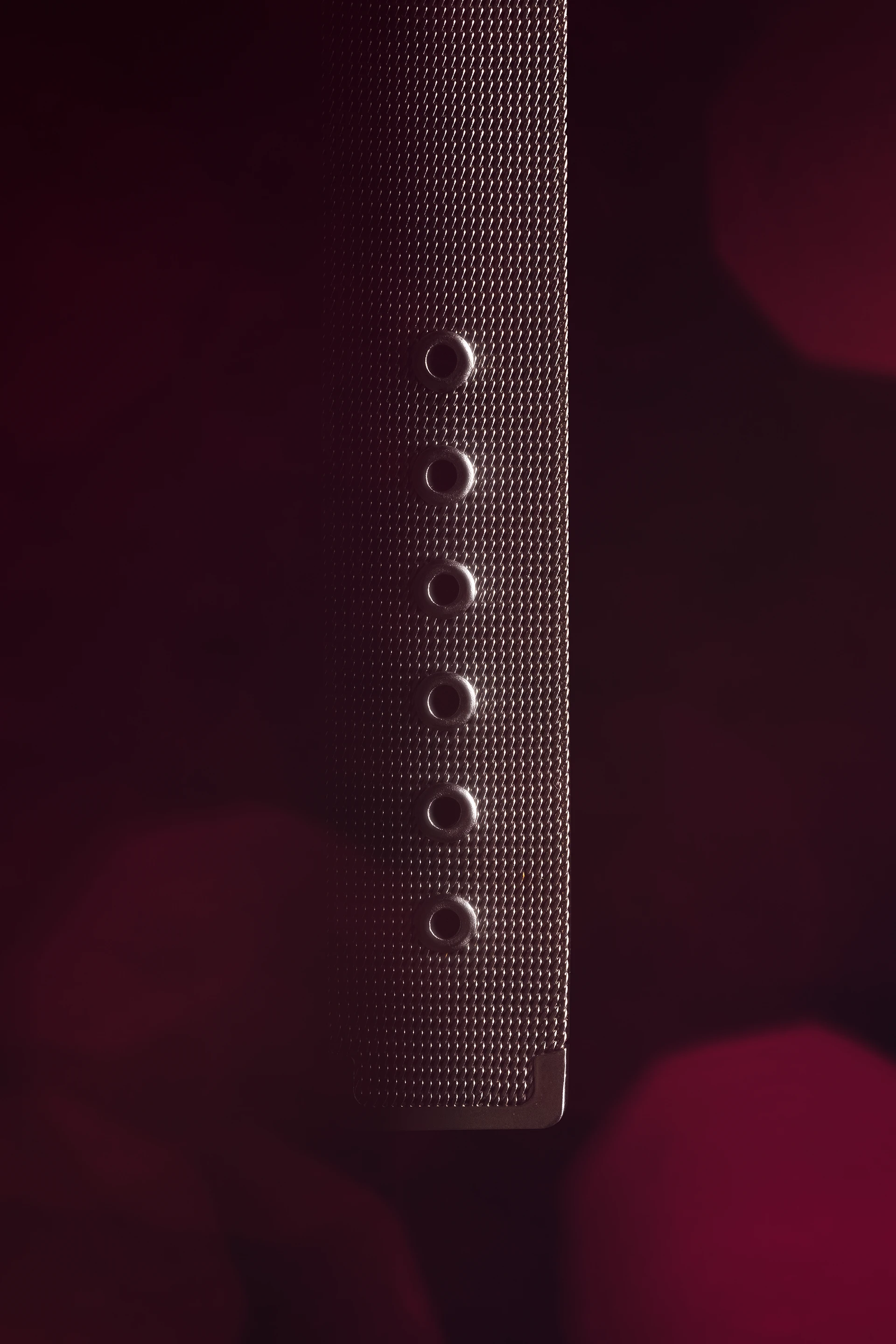 Bracelet milanais gris d'une montre Mercedes sur fond noir et rouge