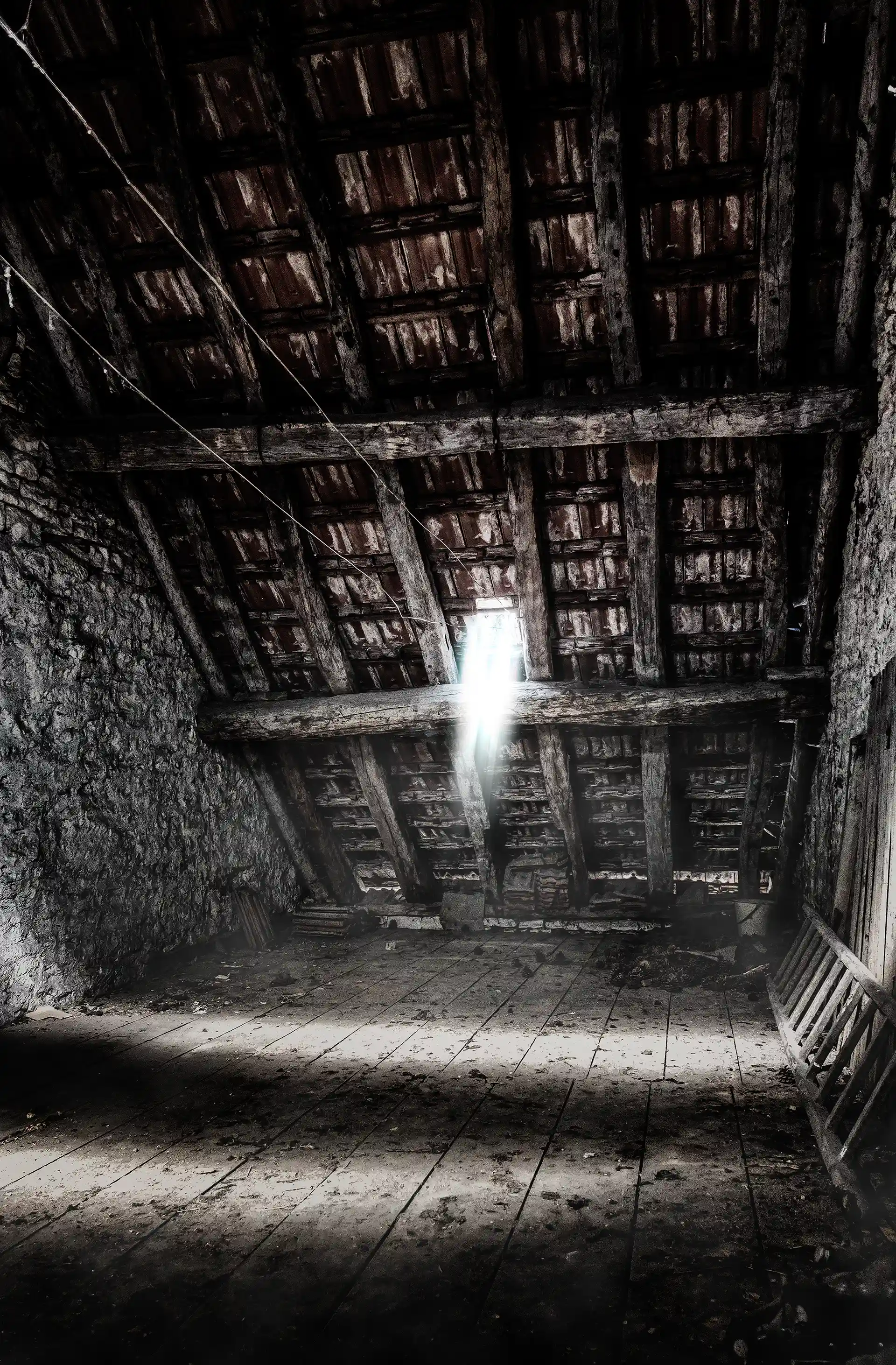 Photo urbex d'un grenier sombre où la lumière passe par le toit