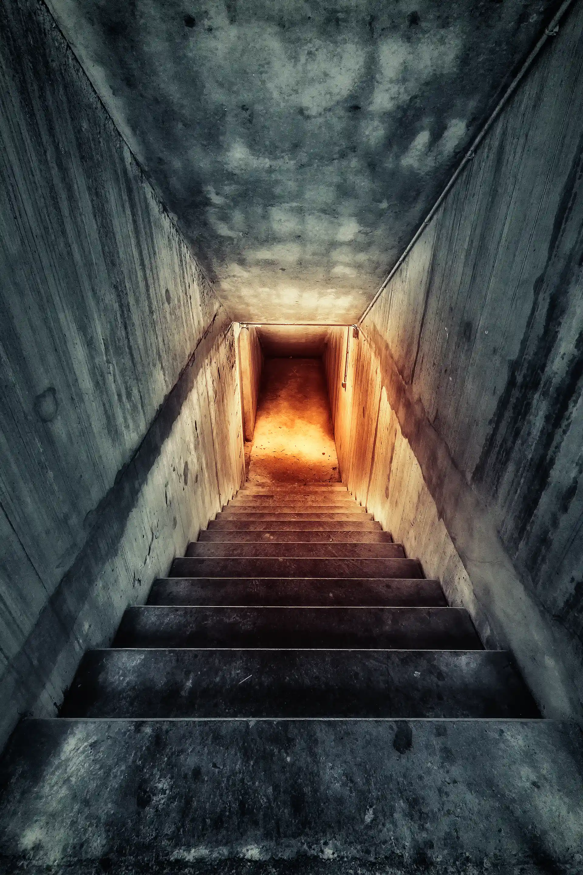 Photo urbex d'un escalier aux teintes froides avec une des teintes chaudes au bout