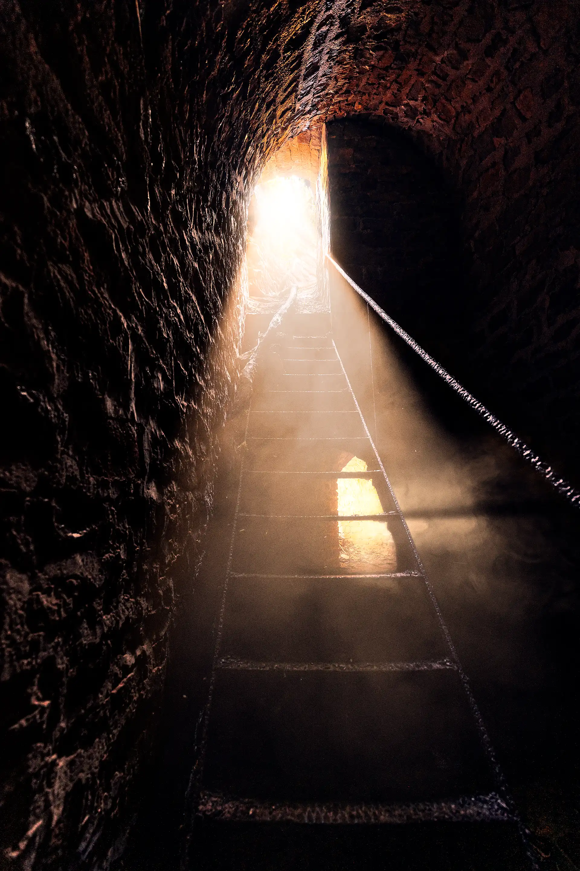 Escalier d'un site urbex, le fort de Varois en Côte d'Or, donnant sur une ouverture qui laisse passer une forte lumière