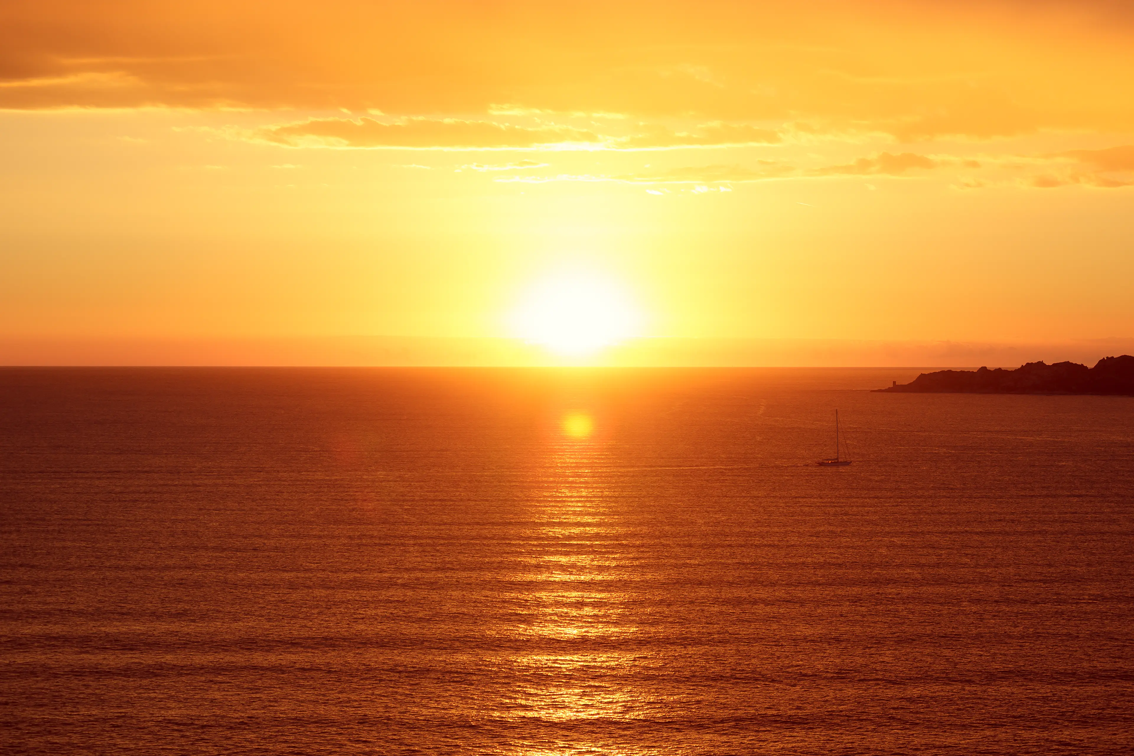 Petit navire qui navigue sur la mer au coucher du soleil avec des teintes chaudes
