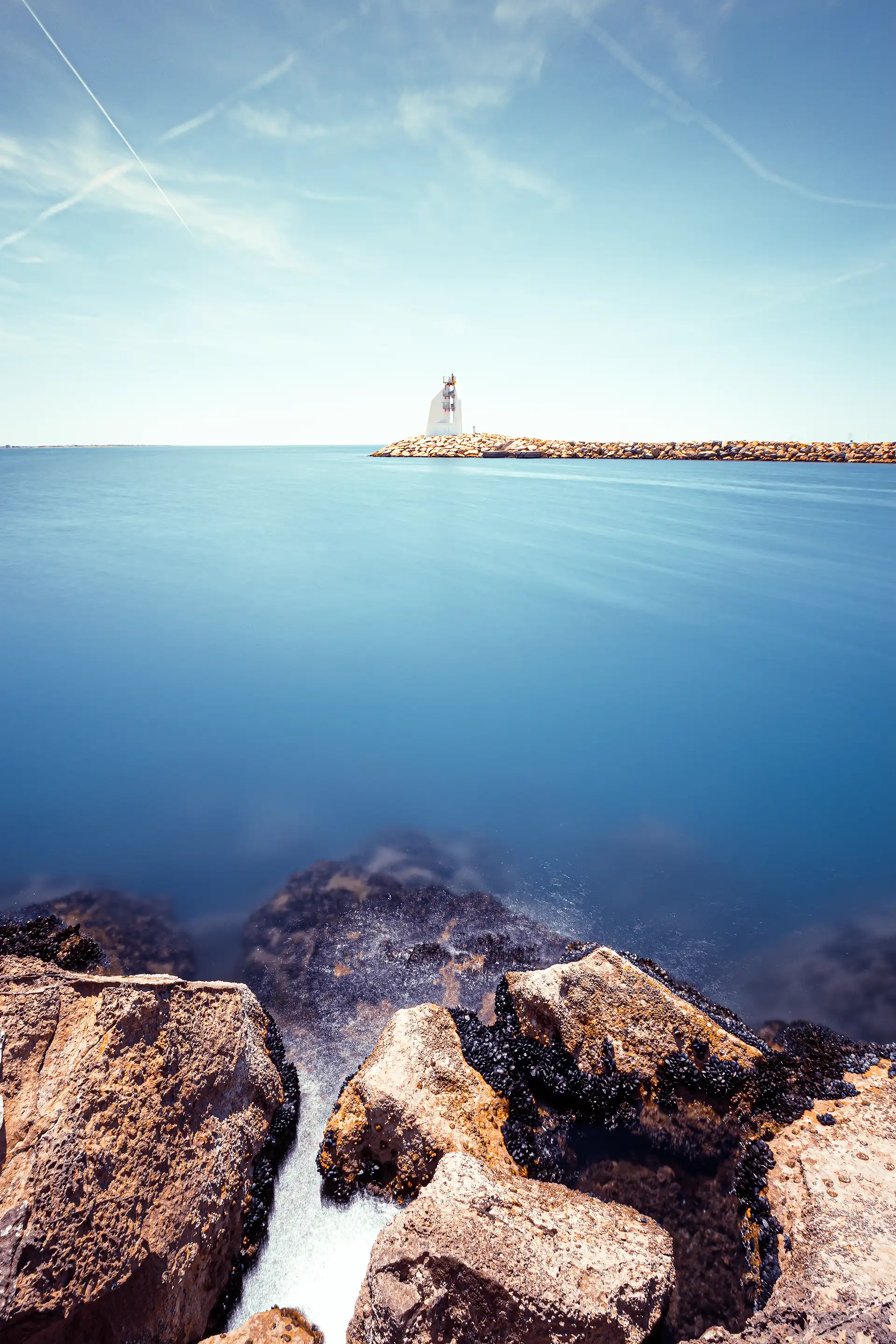Pose longue sur une mer bleue avec un phare au Grau-du-Roi dans le Gard