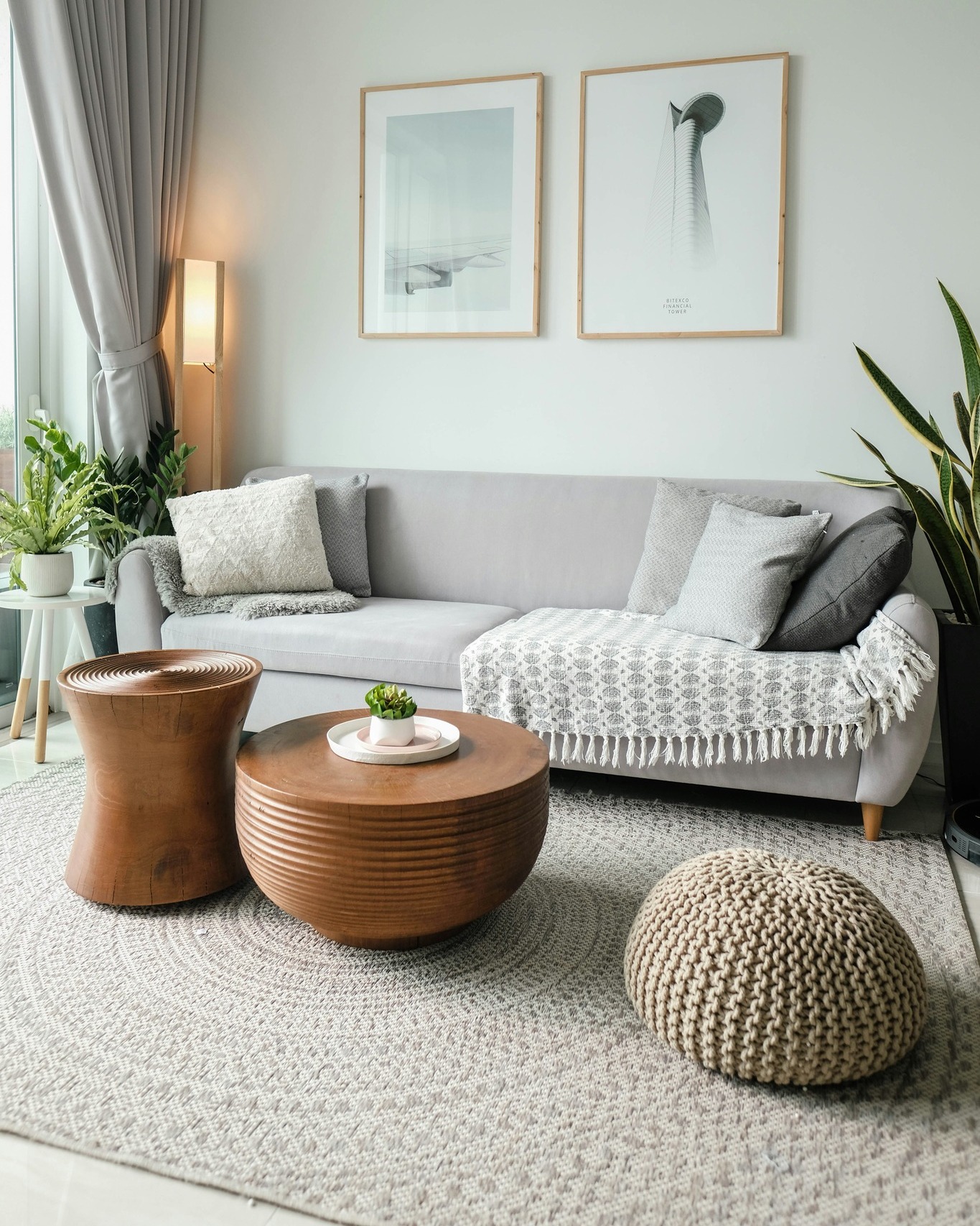 Hubane põhjamaise disainiga elutuba halli diivani, unikaalsete puidust diivanilaudade ja kootud tumbaga.