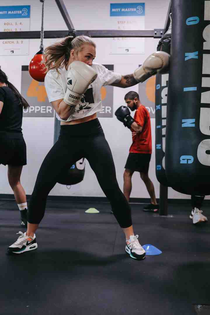 A person looking strong and empowered while hitting a heavy bag in a boxing gym - boxing classes utah