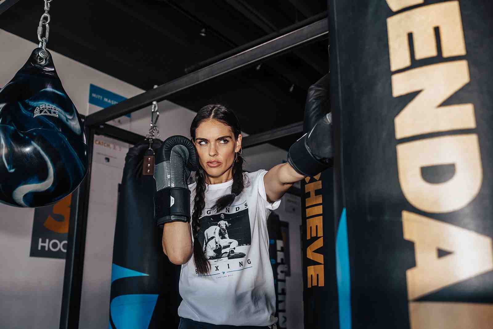 A woman executing a powerful cross punch on a heavy bag at Legends Boxing - boxing for women
