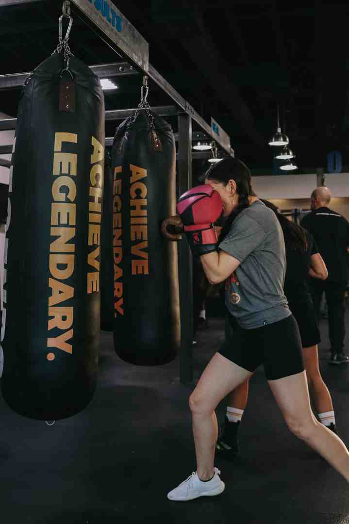 person mid-punch on a heavy bag - gym with punching bag