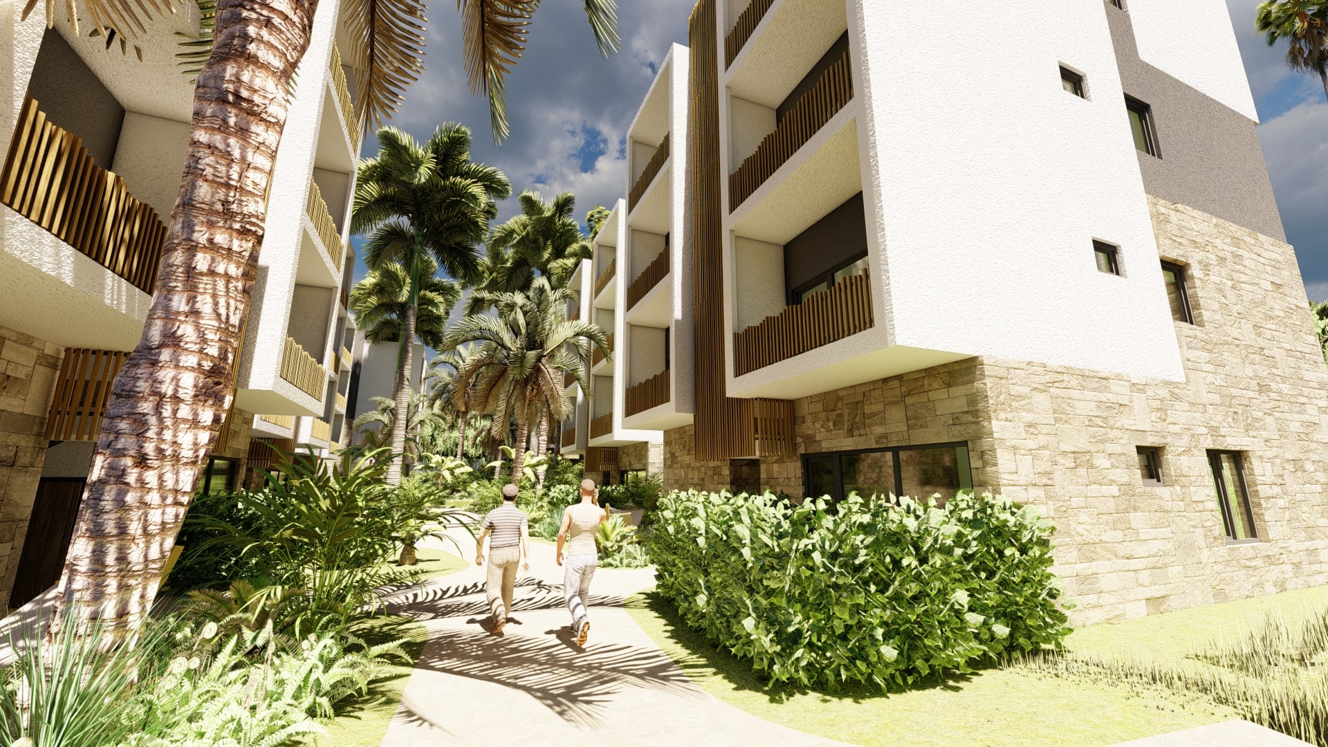 Two people walk along a stone pathway at the VELA resort, surrounded by modern buildings with stone and white facades and lush tropical vegetation.