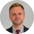 A man with a beard and a red tie is wearing a suit.