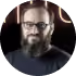 A man with a beard and glasses is wearing a blue shirt.