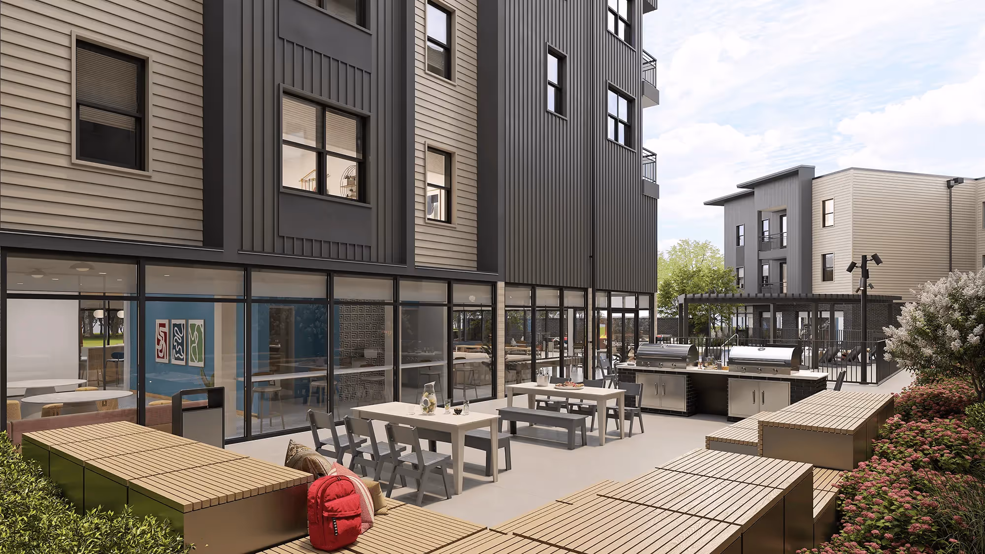 Outdoor courtyard and grilling area with picnic tables and lush landscaping at Global College Station, College Station, TX, offering student outdoor social space.