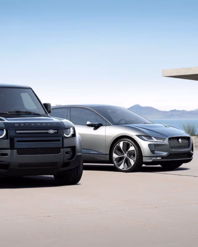 A Black Land Rover Defender and Silver Jaguar parked next to each other