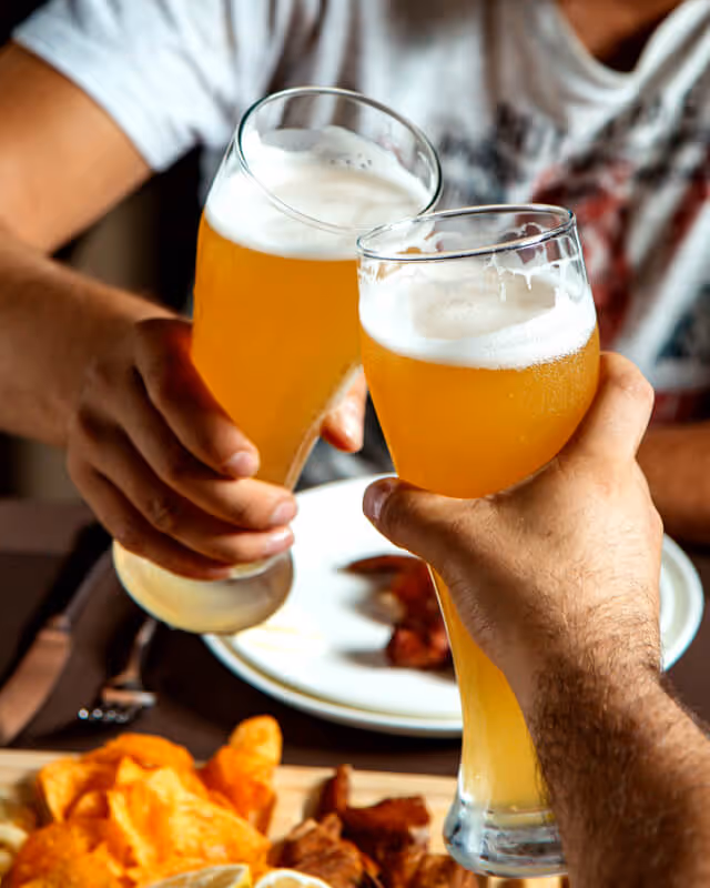 Couple toasting with beers over a pub lunch
