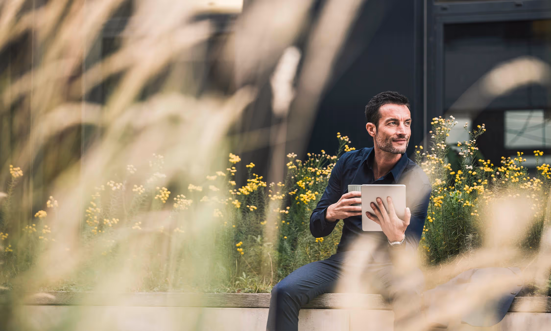Man in courtyard with coffee and tablet