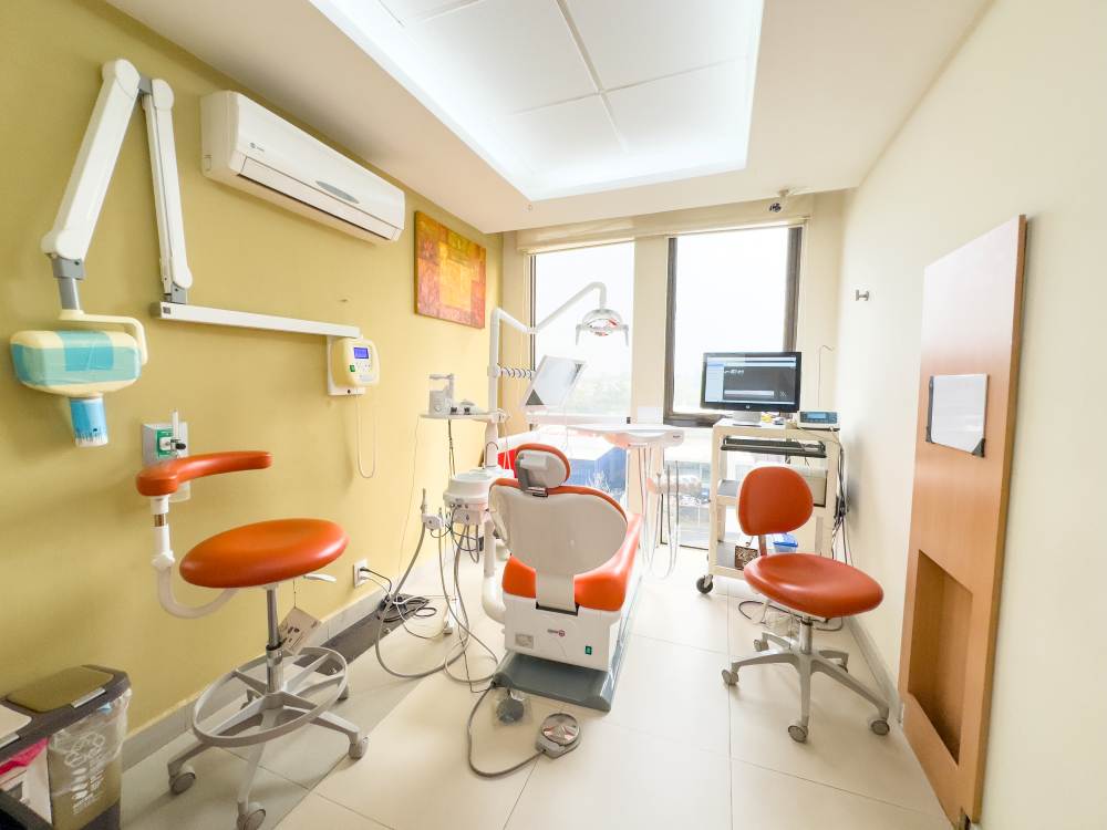 Dental clinic chair and apparatuses such as xray and computer. There is a large widnow overlooking from the building onto the street. 