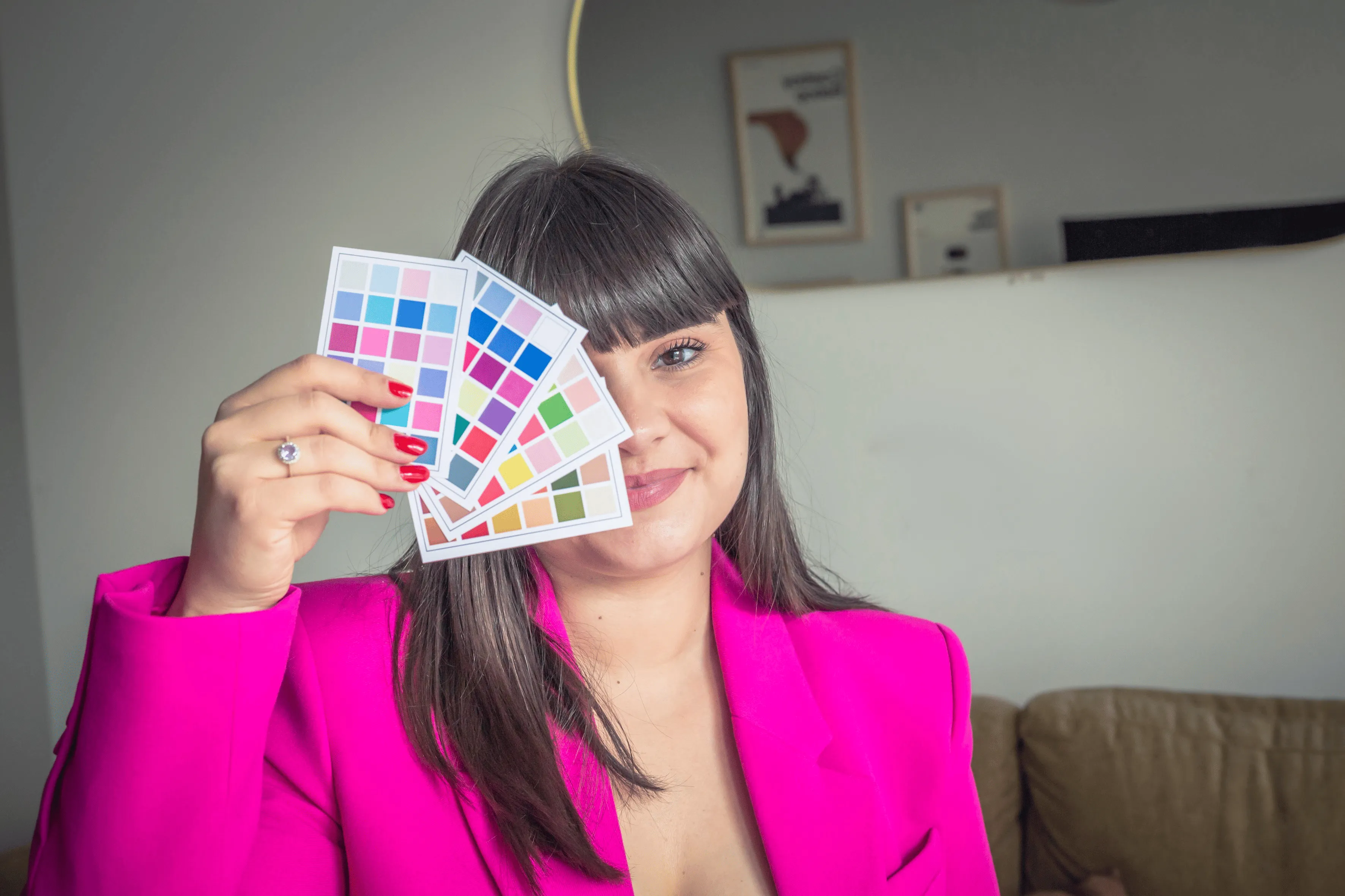 Frangie, conseillère en image souriante en veste rose fuchsia tenant des palettes de couleurs pour une séance de colorimétrie
