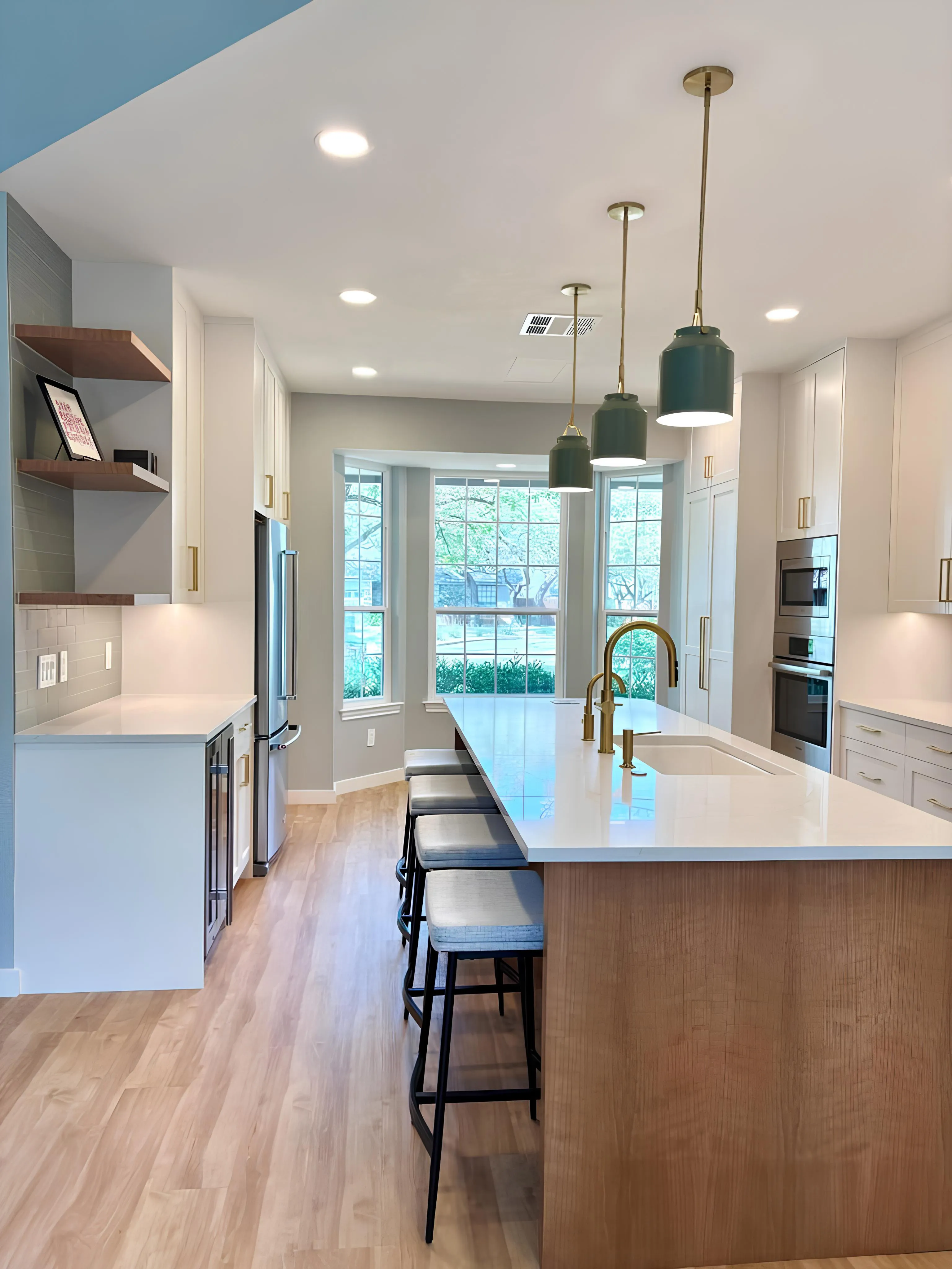 Modern kitchen with island, pendant lights, and large window.