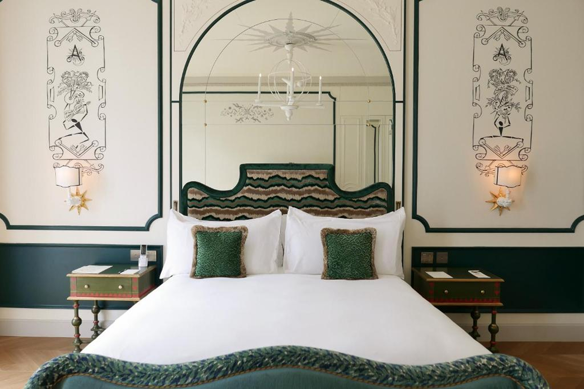 Chambre de L’Aventure avec tête de lit verte, fauteuil et tapis à motifs.