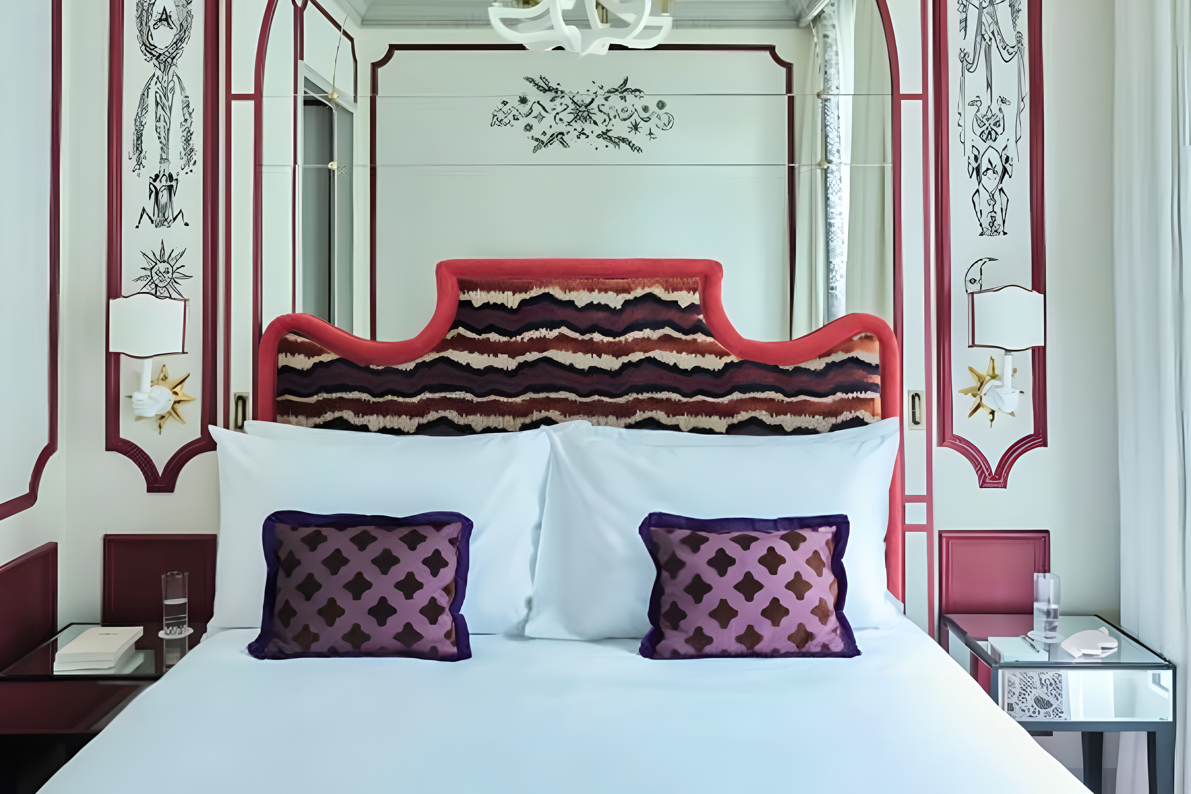 Chambre de L’Aventure avec lit à tête de lit rouge et fauteuil assorti.