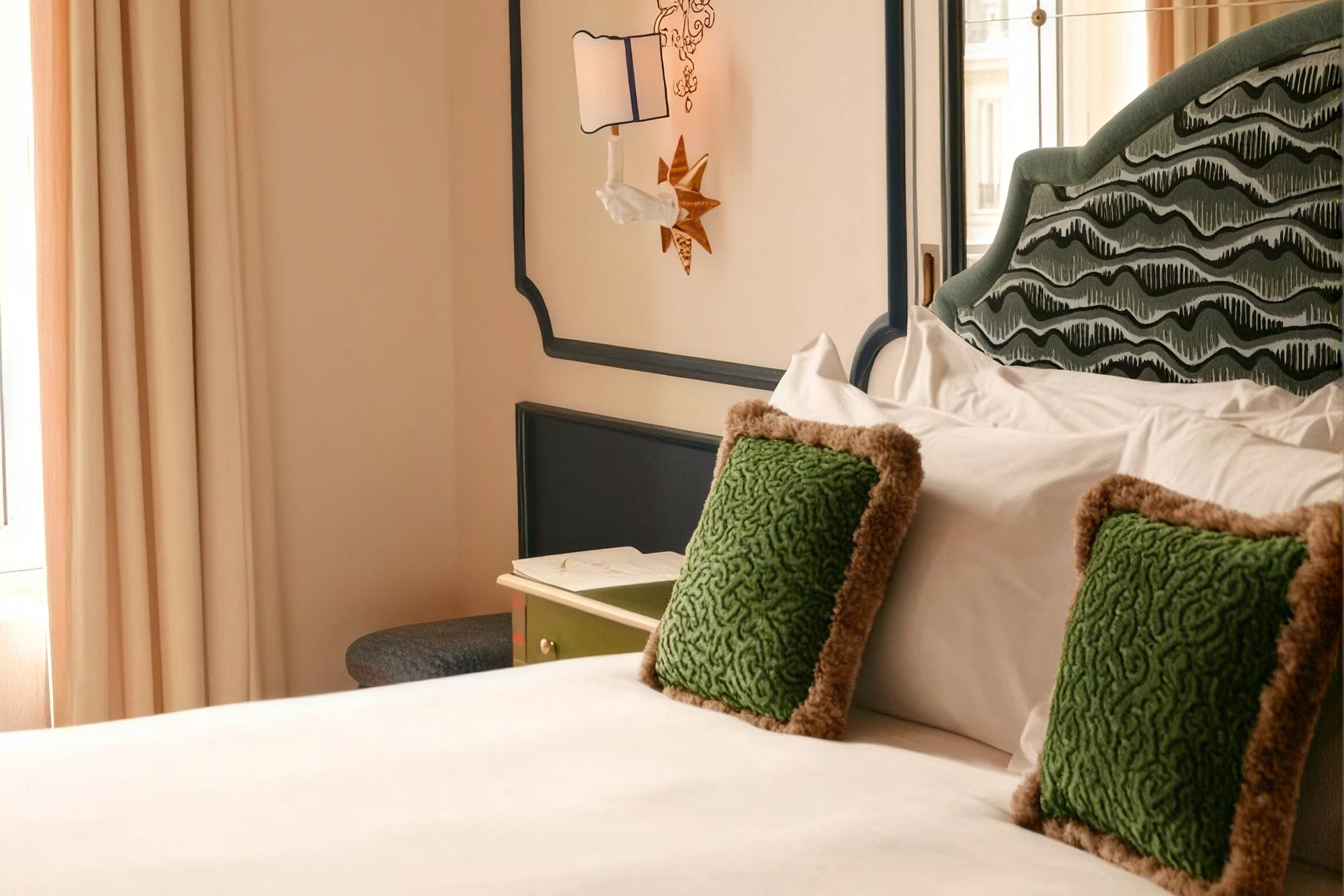 Chambre de L’Aventure avec tête de lit verte, fauteuil et tapis à motifs.