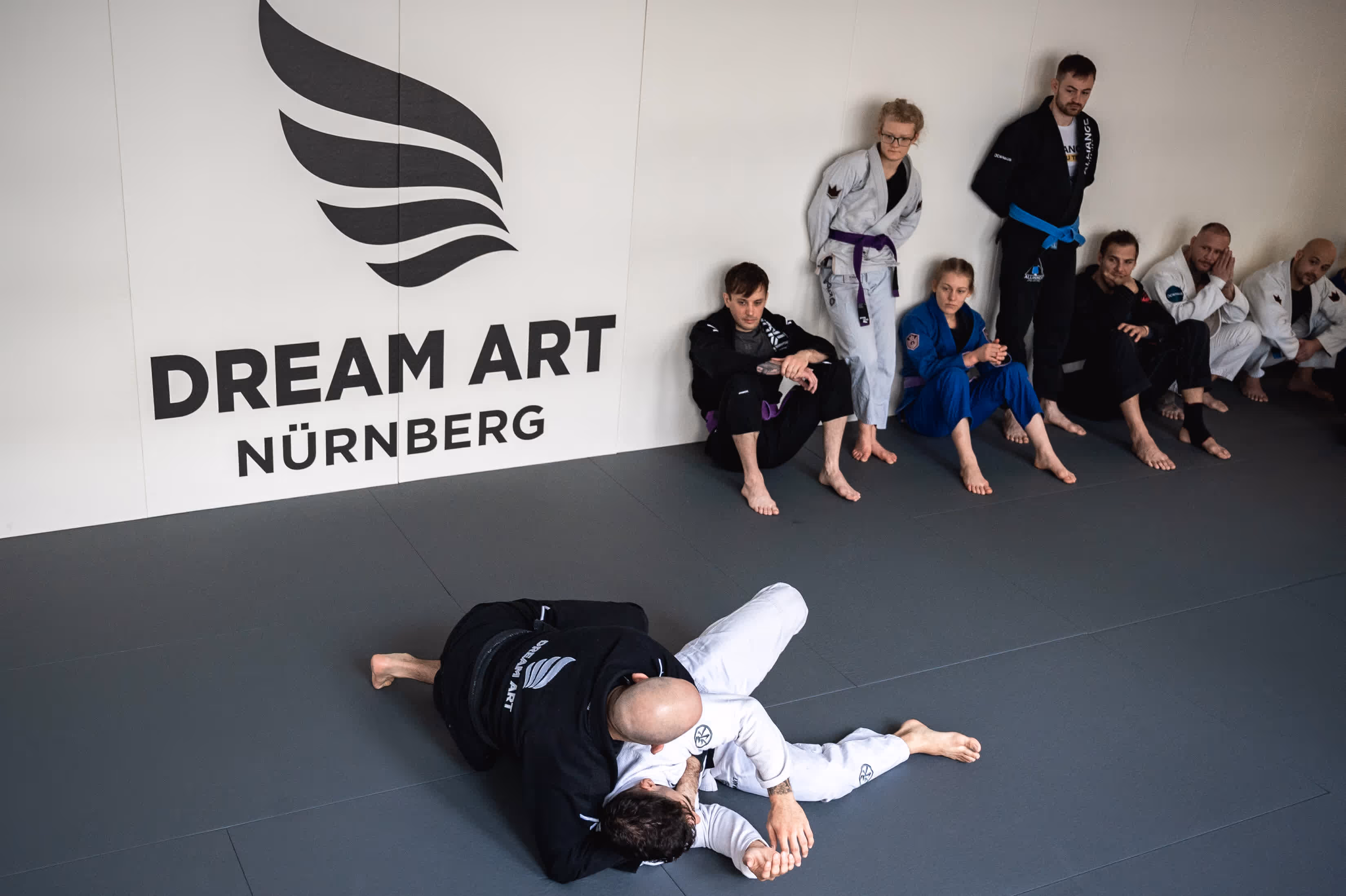 BJJ-Trainingspartner in blauen Gis begrüßen sich und bereiten sich auf eine Trainingseinheit vor.