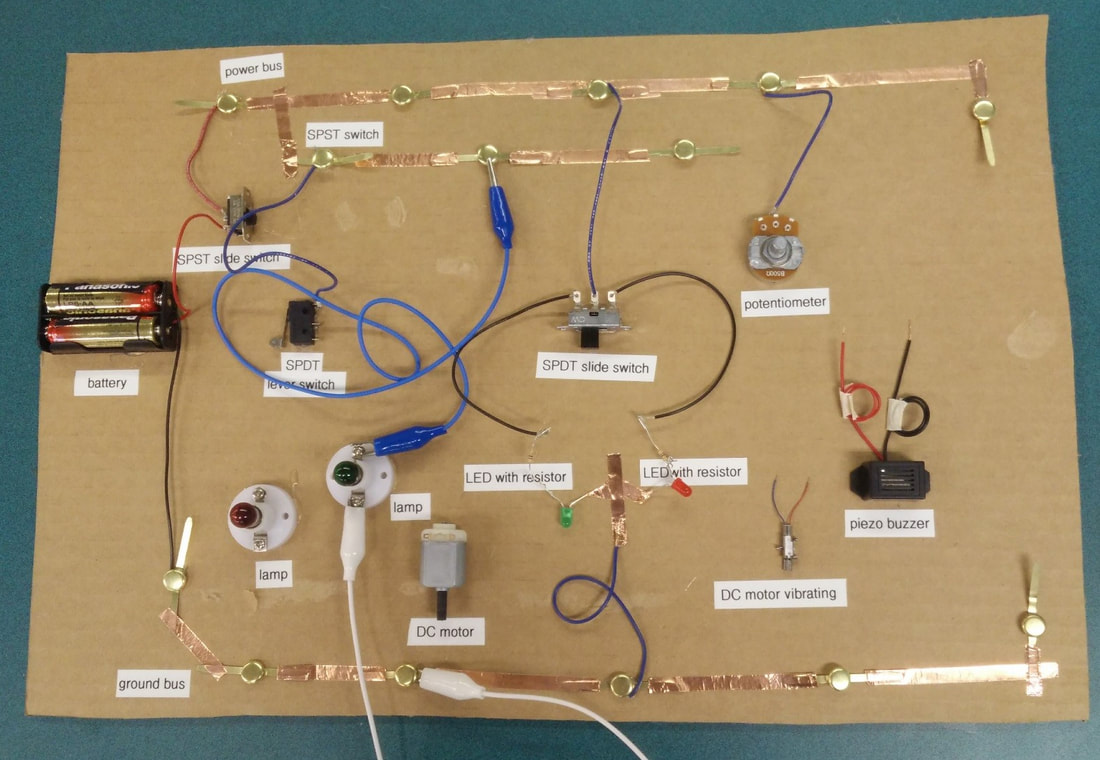 Labeled electronic circuit board with switches, LEDs, motor, buzzer, and battery connections.