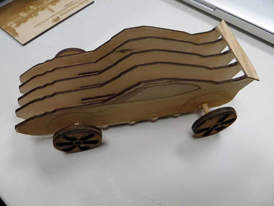 Wooden toy car with wavy design and dark wheels on white surface