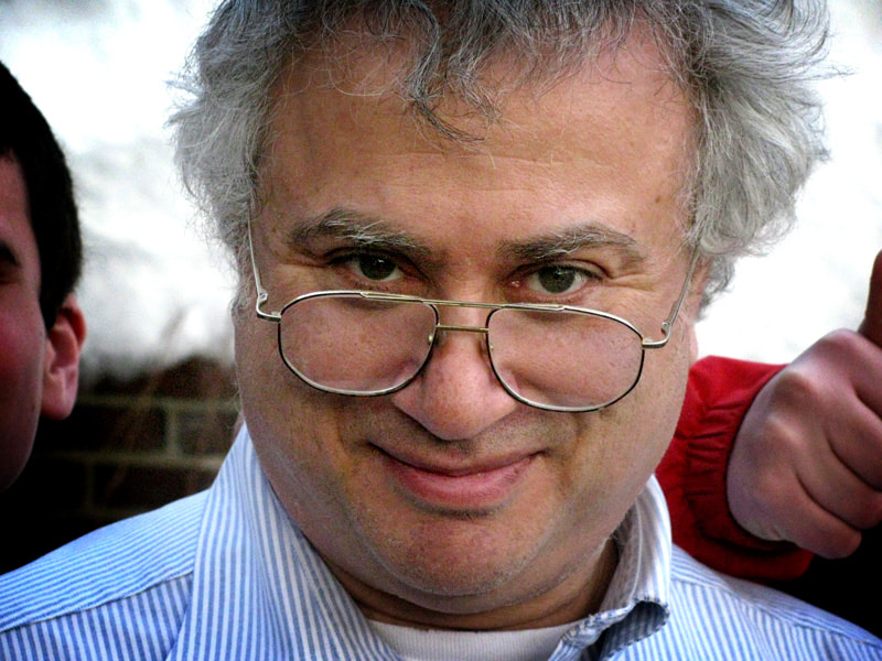 Older man with gray hair and glasses smiling at the camera