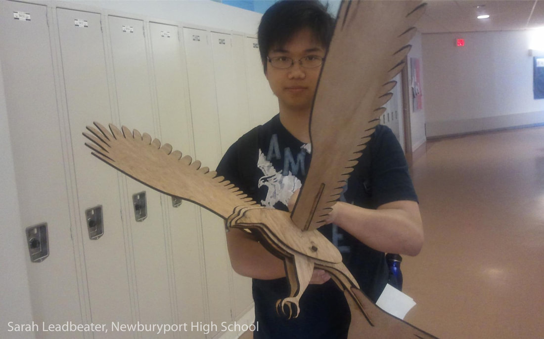Student holding large wooden bird sculpture in school hallway