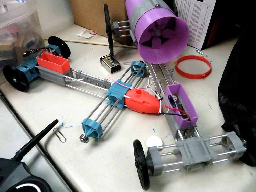 Robotics kit components on desk including motors, purple fan, blue and red parts