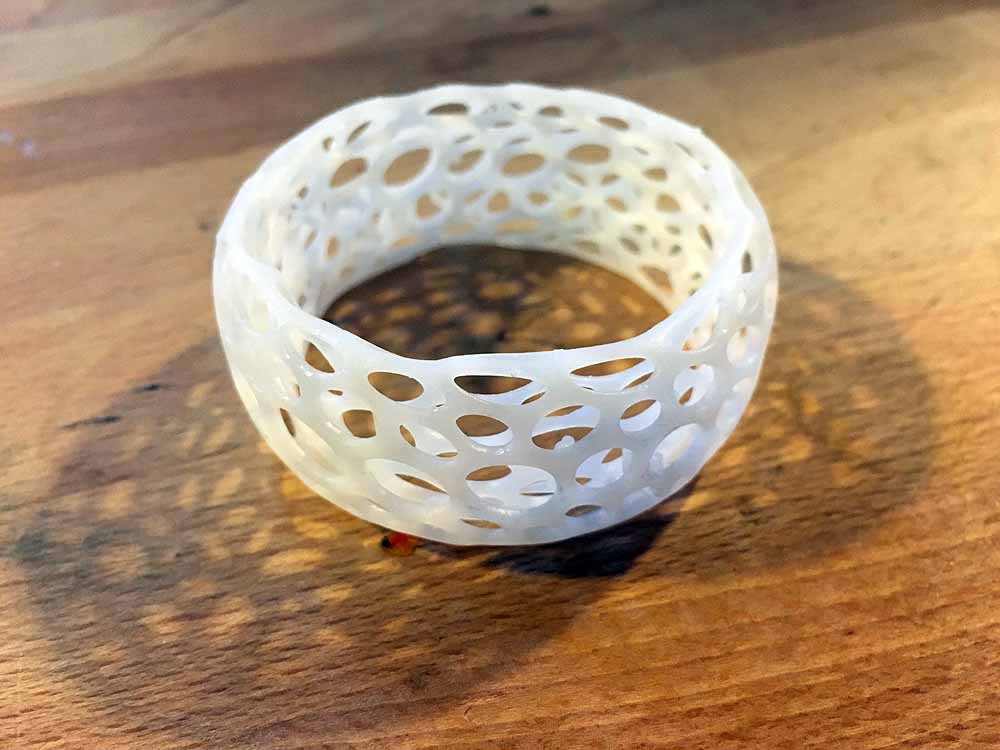 White ceramic lattice bowl filled with brown liquid on wooden surface