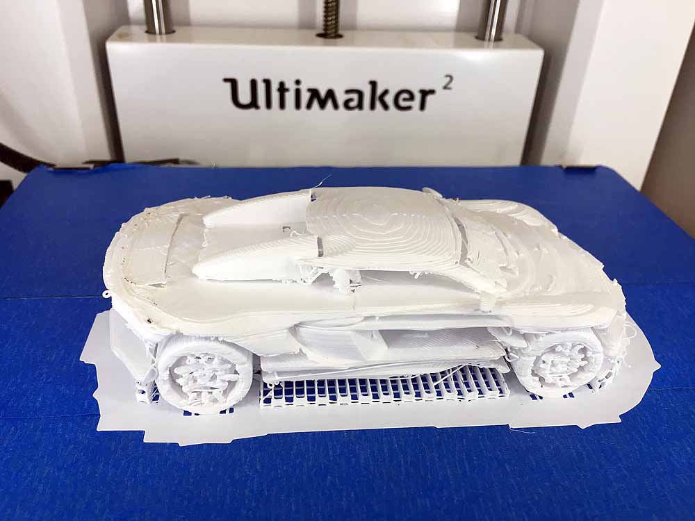 White 3D printed toy car model on blue surface with Ultimaker printer